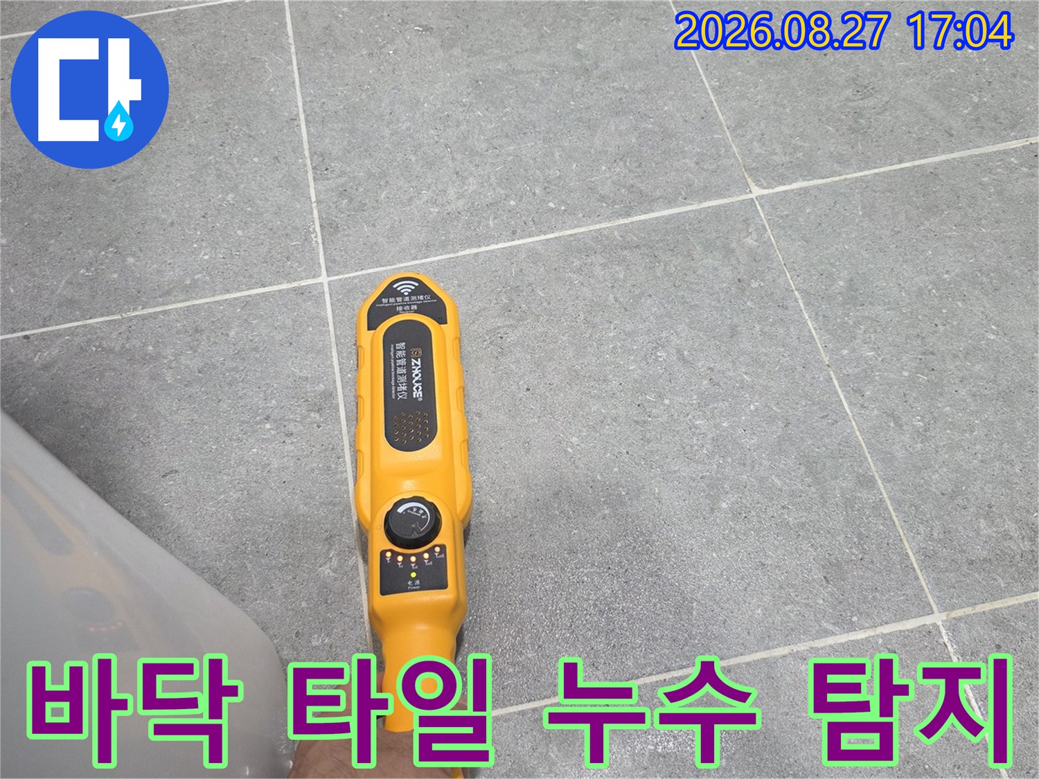 회색 욕실 타일 위-노란색 배관 탐지 장비-사용 모습