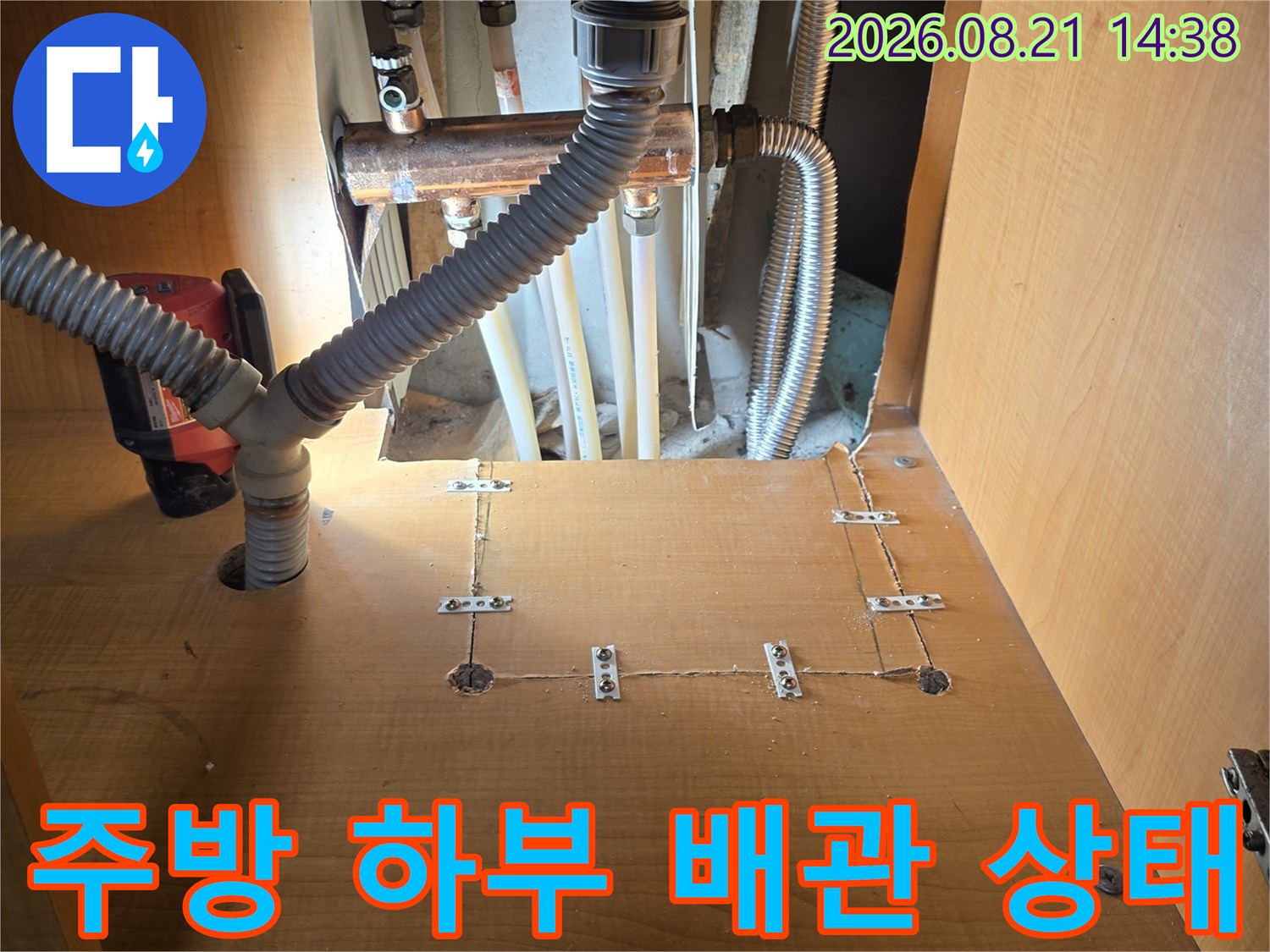 싱크대 밑에 설치된 금속 배관과 굵은 주름관의 연결 모습