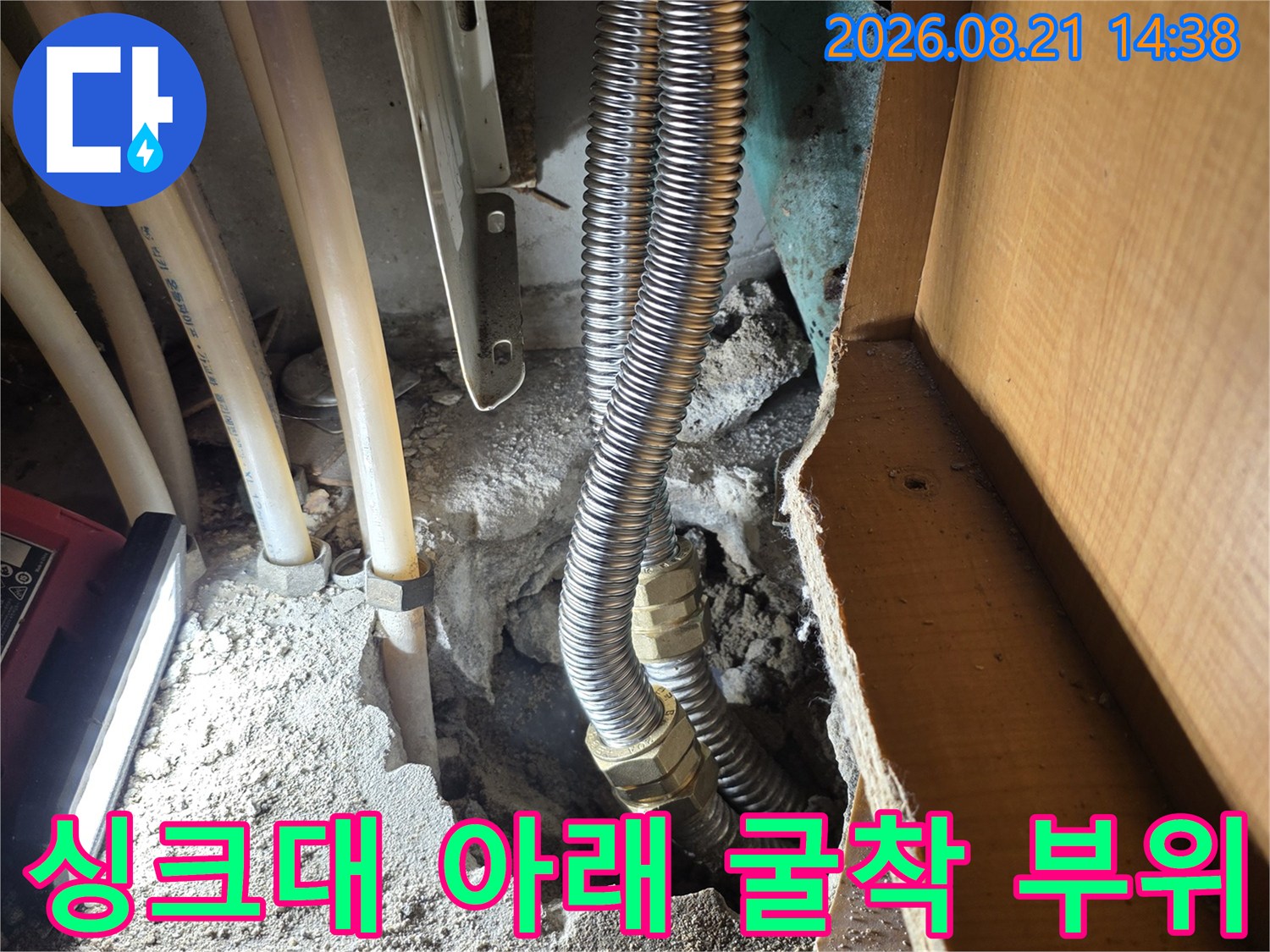 싱크대 하부장 밑바닥을 파내어 드러난 배관과 주변 구조물을 찍은 사진입니다.