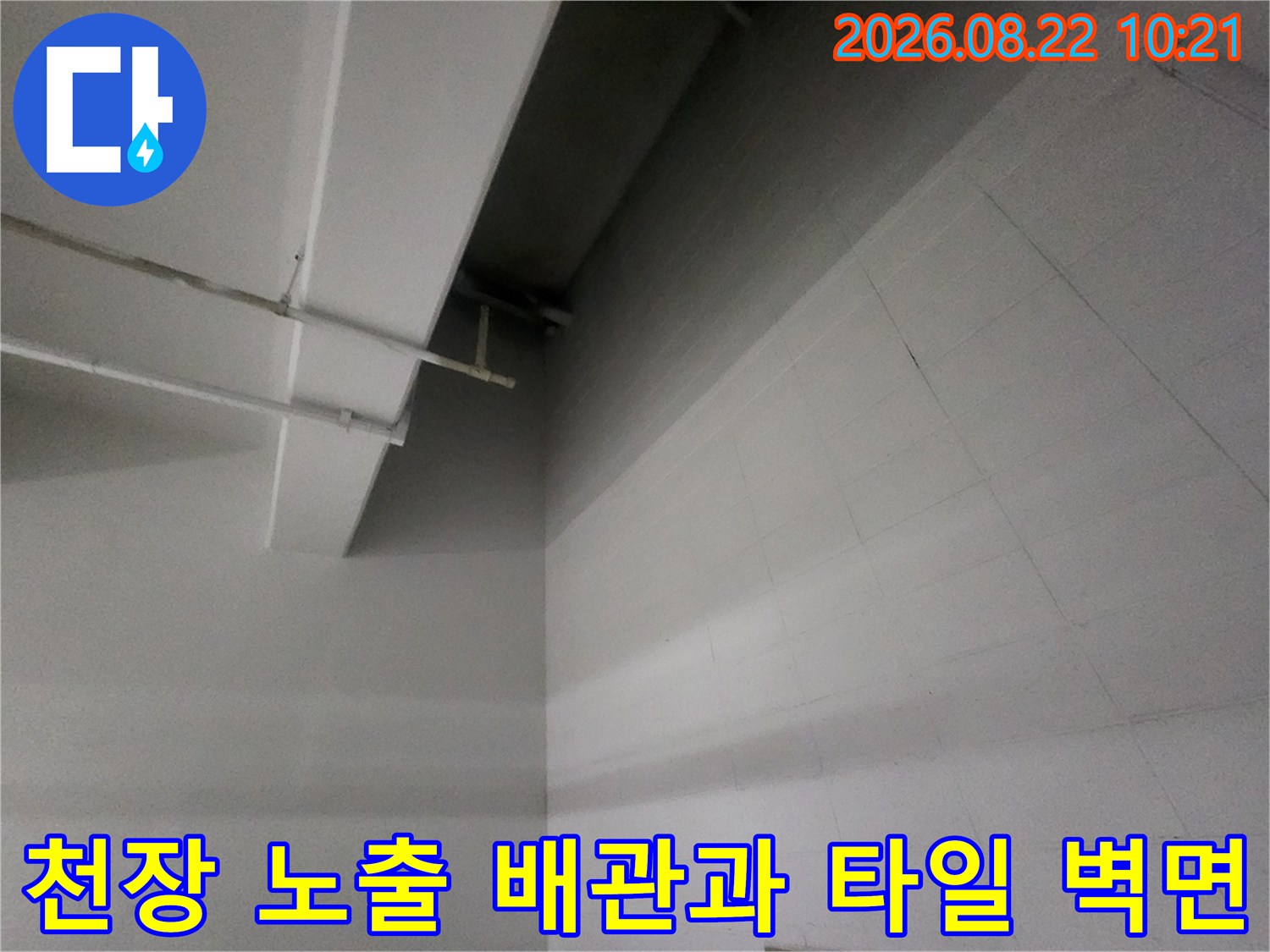 지하주차장 천장 구조물과 흰색 타일 벽면의 상세 모습