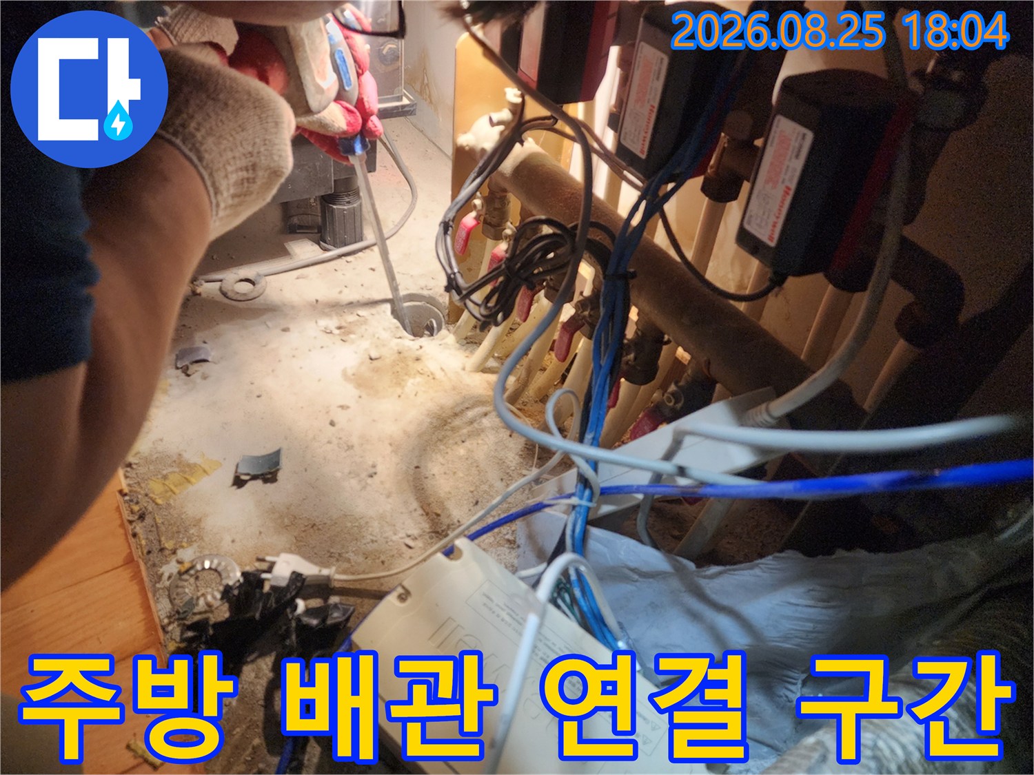 싱크대 밑 공간의 복잡한 배관 구조와 전기 배선들의 모습
