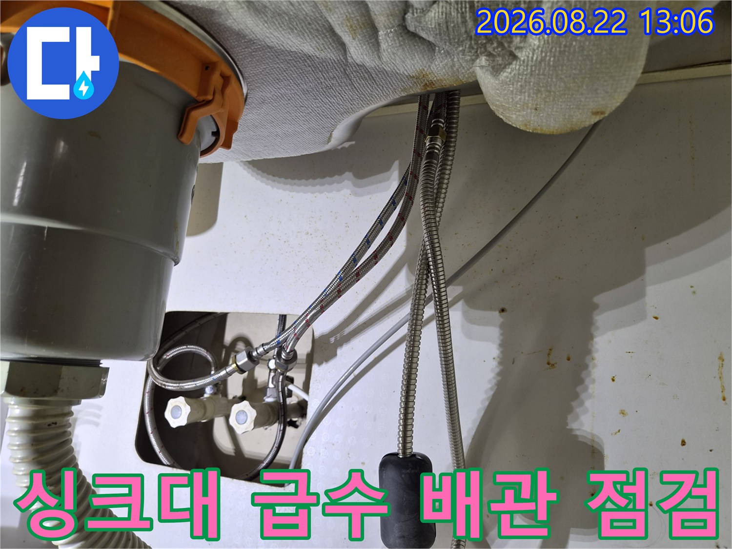싱크대 하단 밸브와 수전 호스가 연결되어 있는 설비 작업 사진입니다.