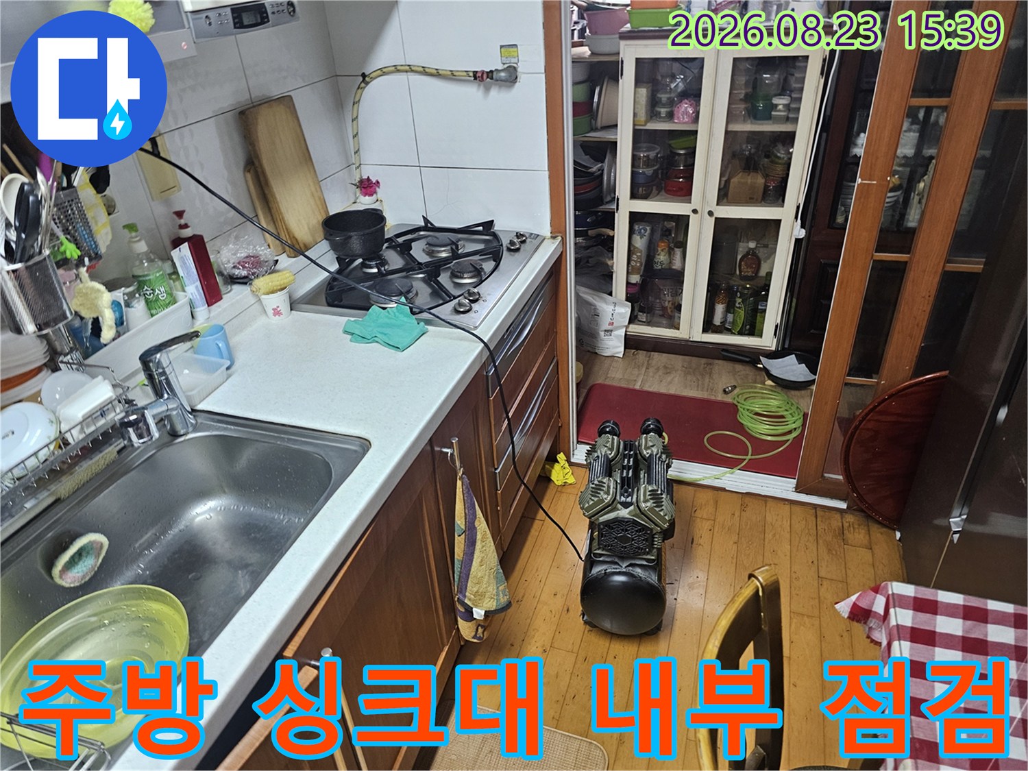 싱크대 하부장 뒤쪽의 복잡한 배관과 가스 탐지 장비 사진