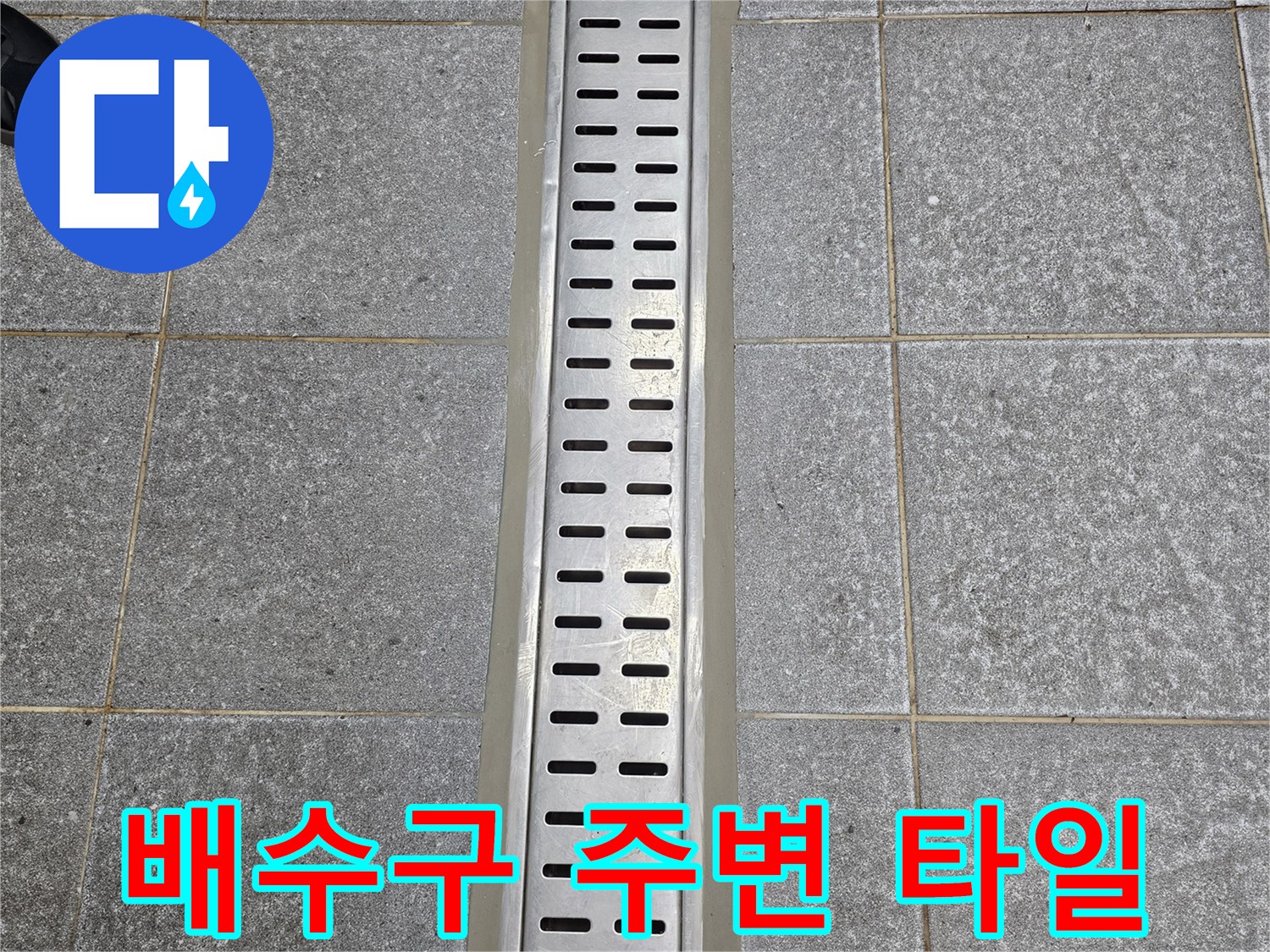 회색 타일과 스테인리스 배수구 트렌치의 접합 부위 사진