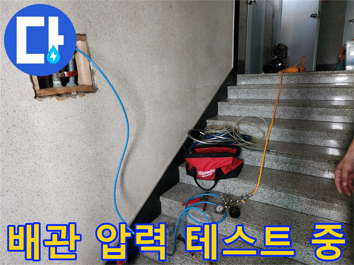 배관에 연결된 파란색 호스를 통해 공압 테스트를 진행하는 장면