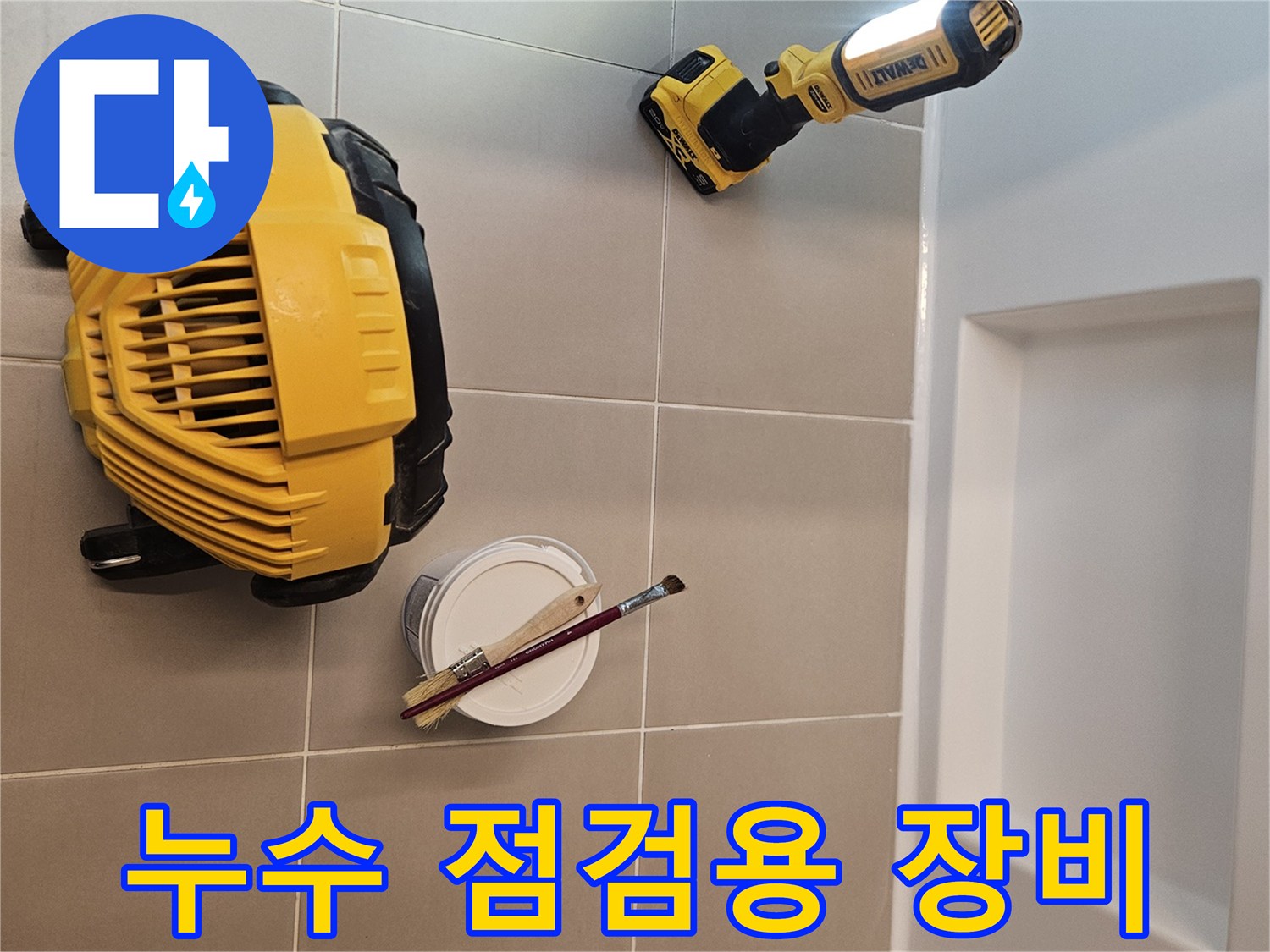 화장실 타일 바닥에 놓인 작업용 조명과 붓 세트