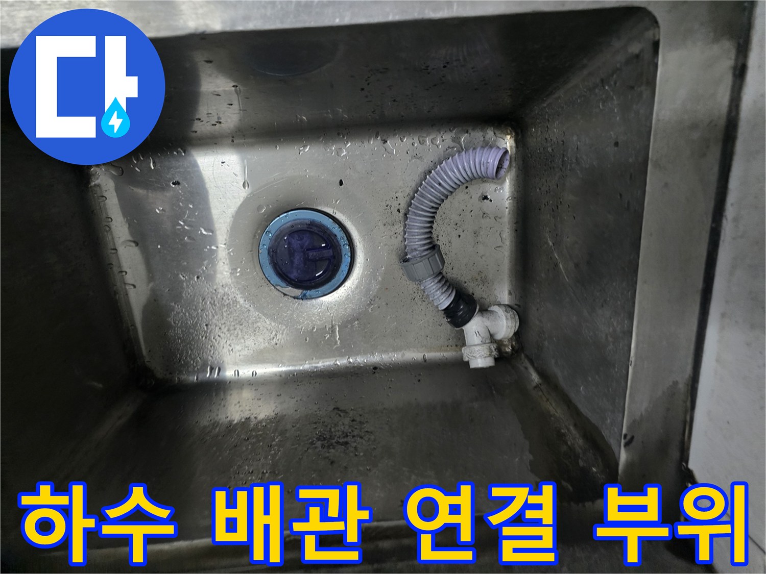 싱크대 내부의 하얀색 PVC 부속과 회색 주름관 상세