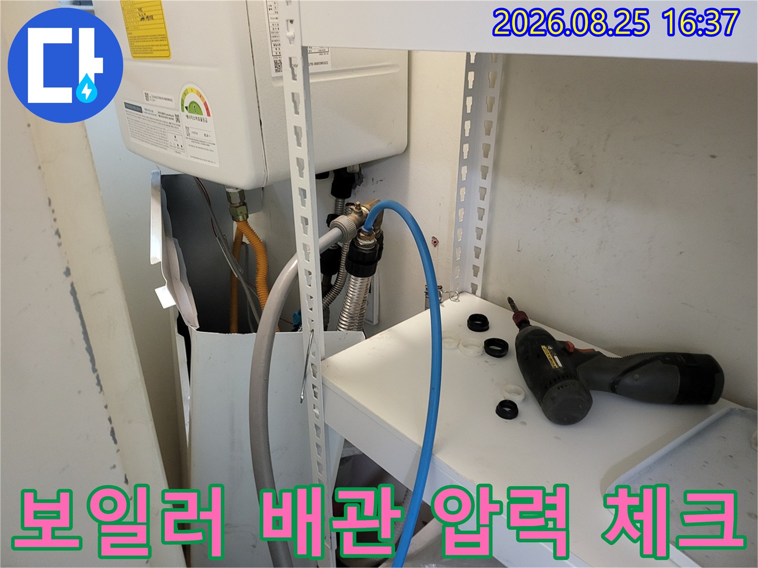 보일러 하단에 연결된 파란색 호스와 배관 부속의 모습입니다.