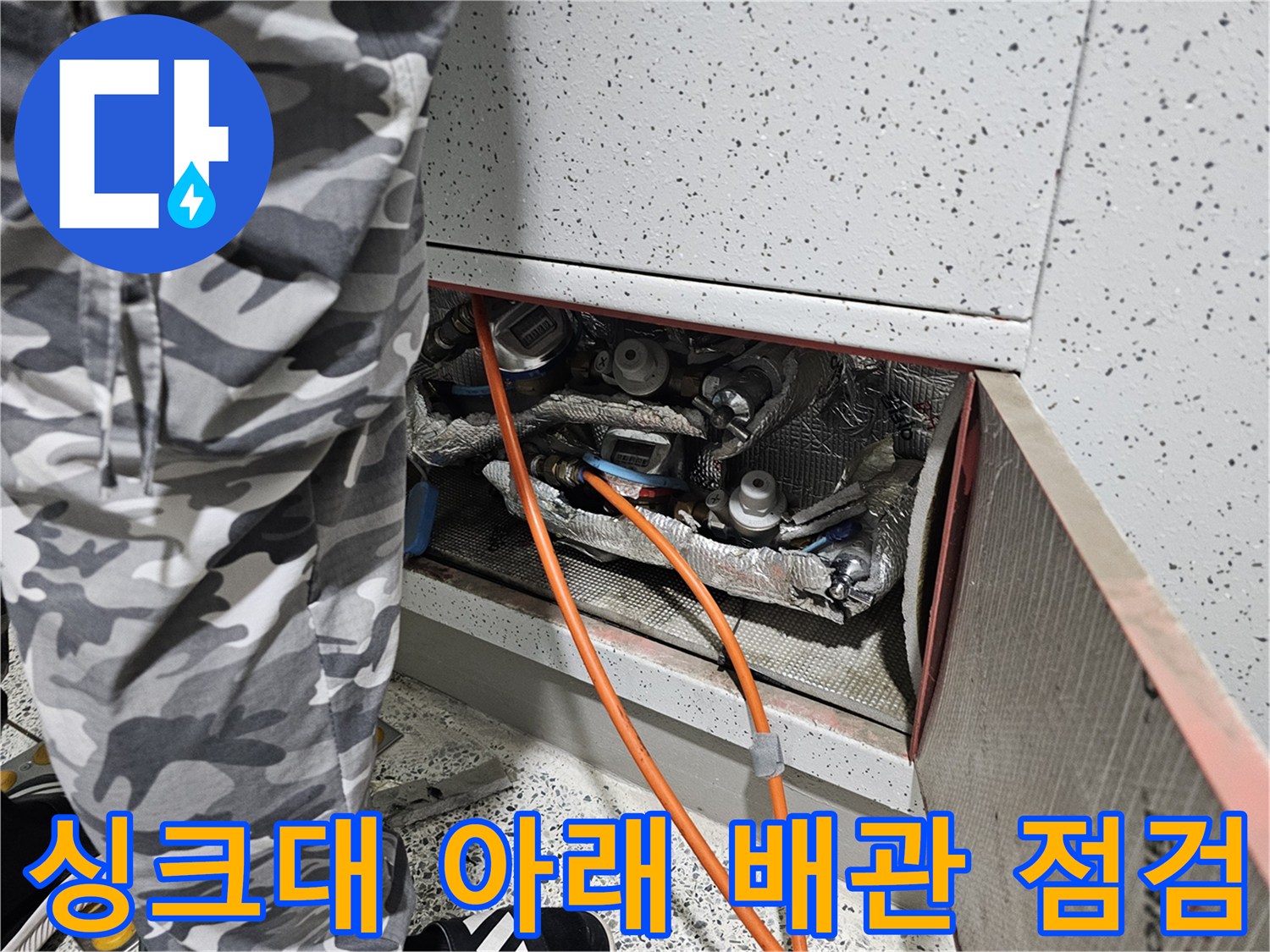 싱크대 하단 배관의 은색 보온재와 연결된 주황색 호스