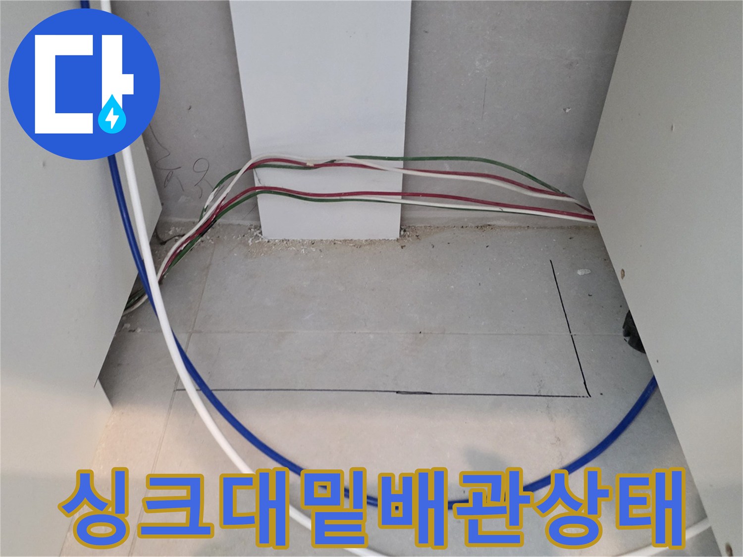 싱크대 아래 노출된 파란색 호스와 전기 선들