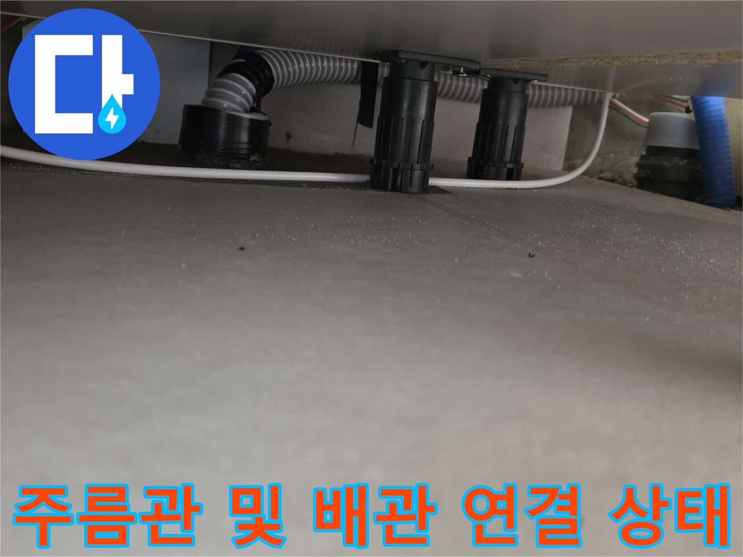 싱크대 하단에 배치된 회색 주름관과 검은색 부속들