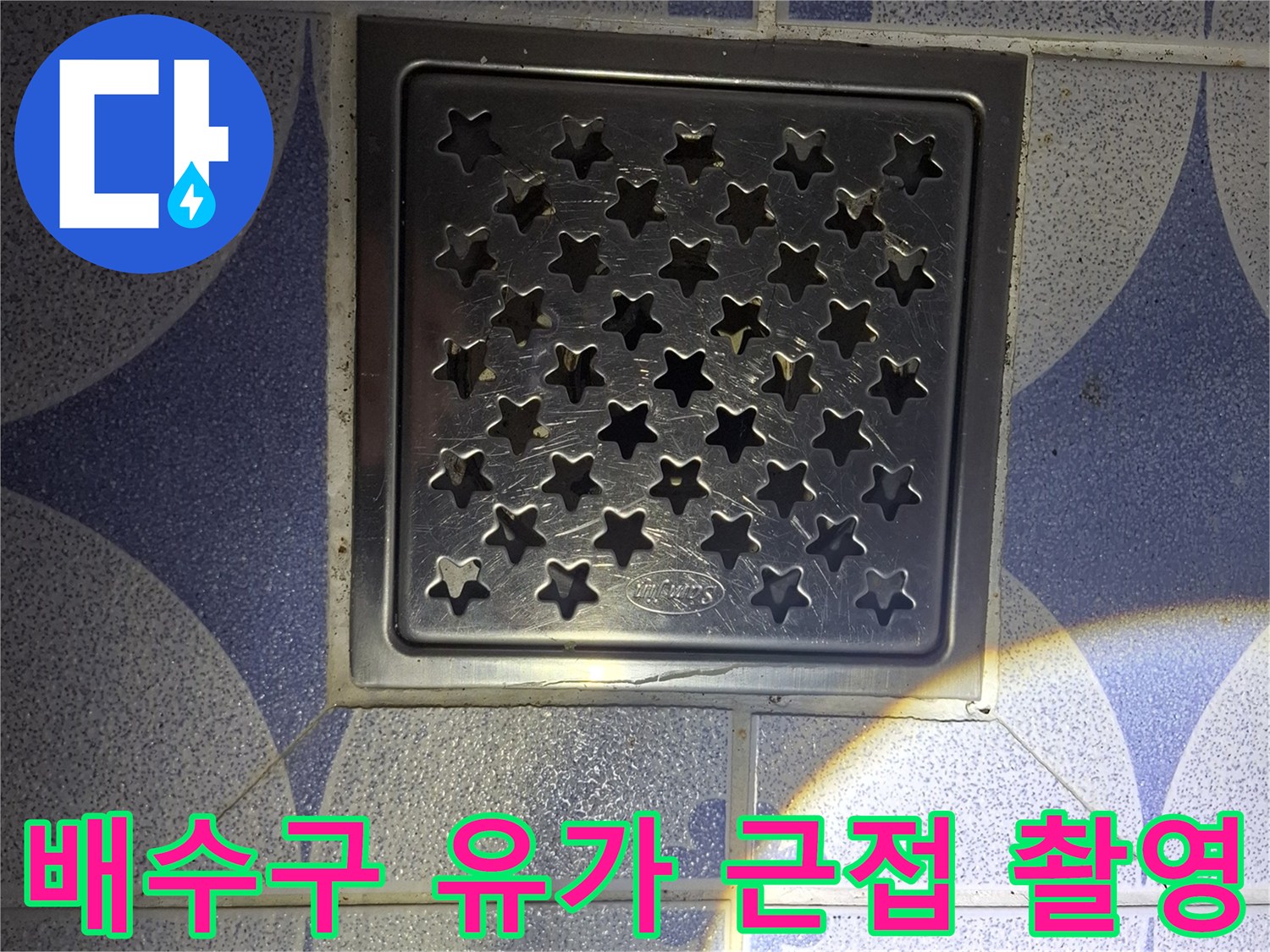 스테인리스 재질의 배수구와 푸른색 타일 바닥