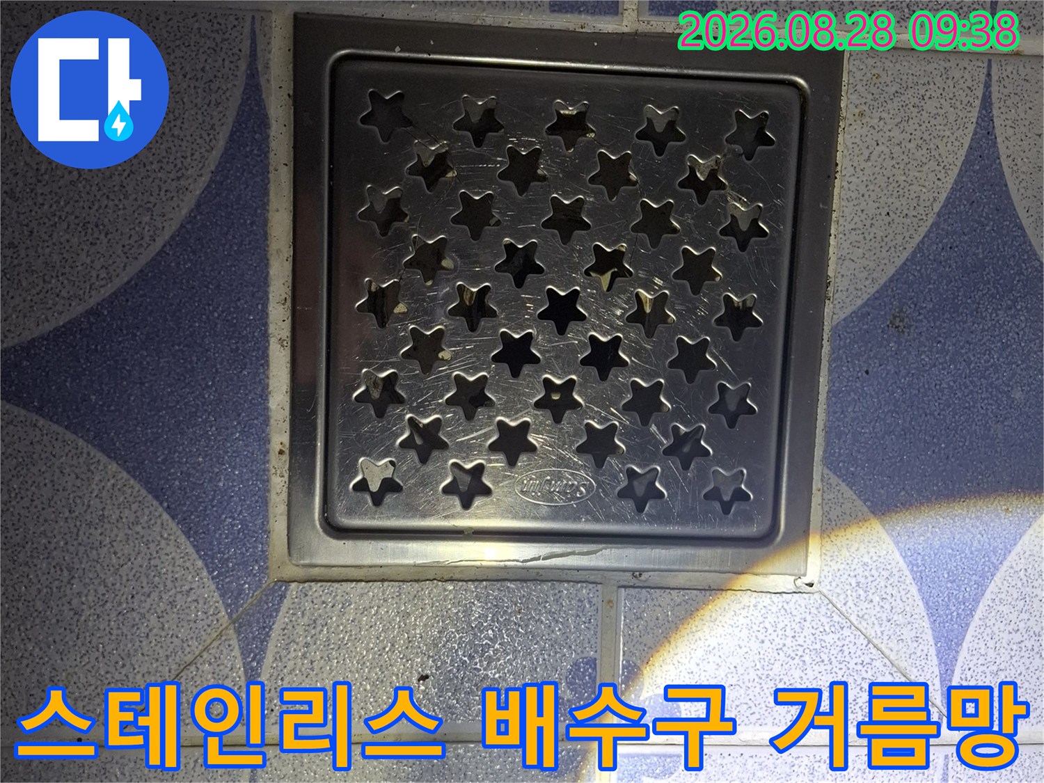 푸른색 패턴 타일 위에 설치된-스테인리스 사각 배수구 사진입니다.