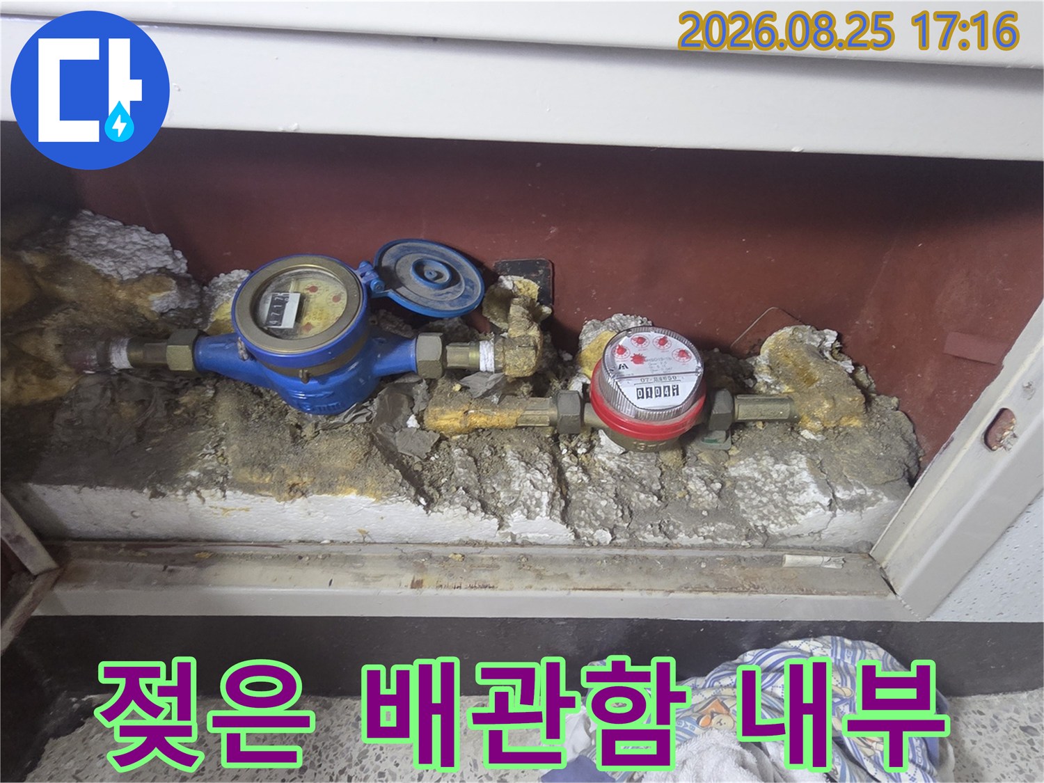 수도 계량기 주변의 습기와 배관 부식 상태를 보여줍니다.
