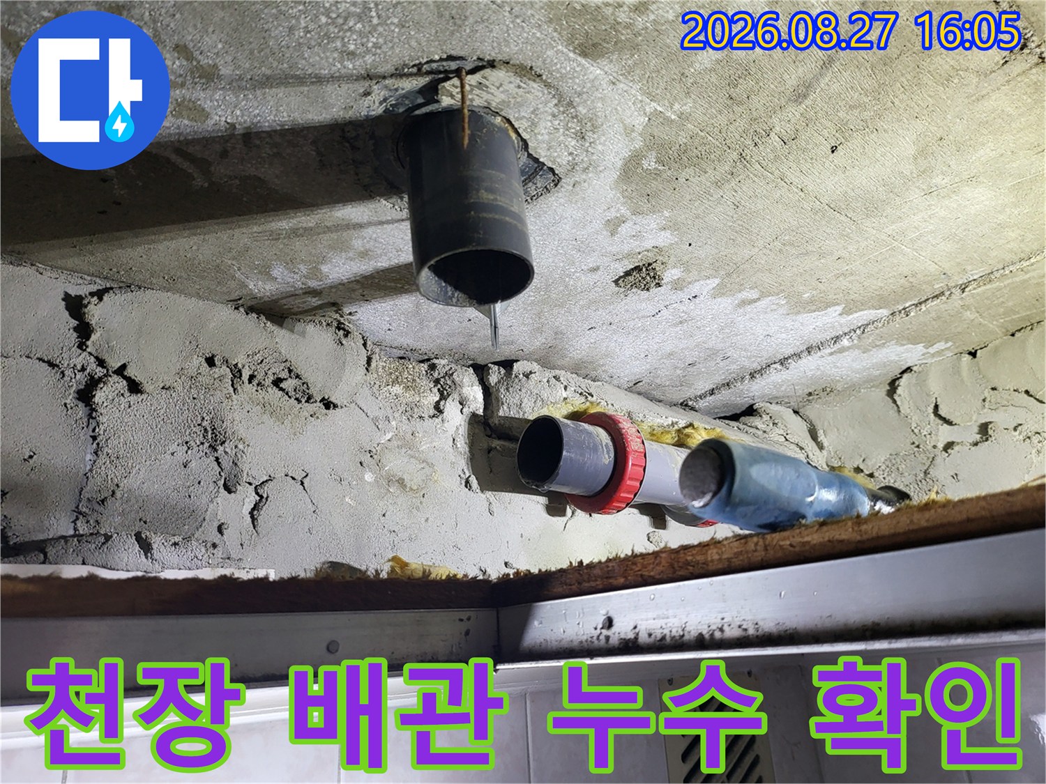 화장실 천장 내부의 검은색 배관 연결 부위에서 물이 떨어지는 모습
