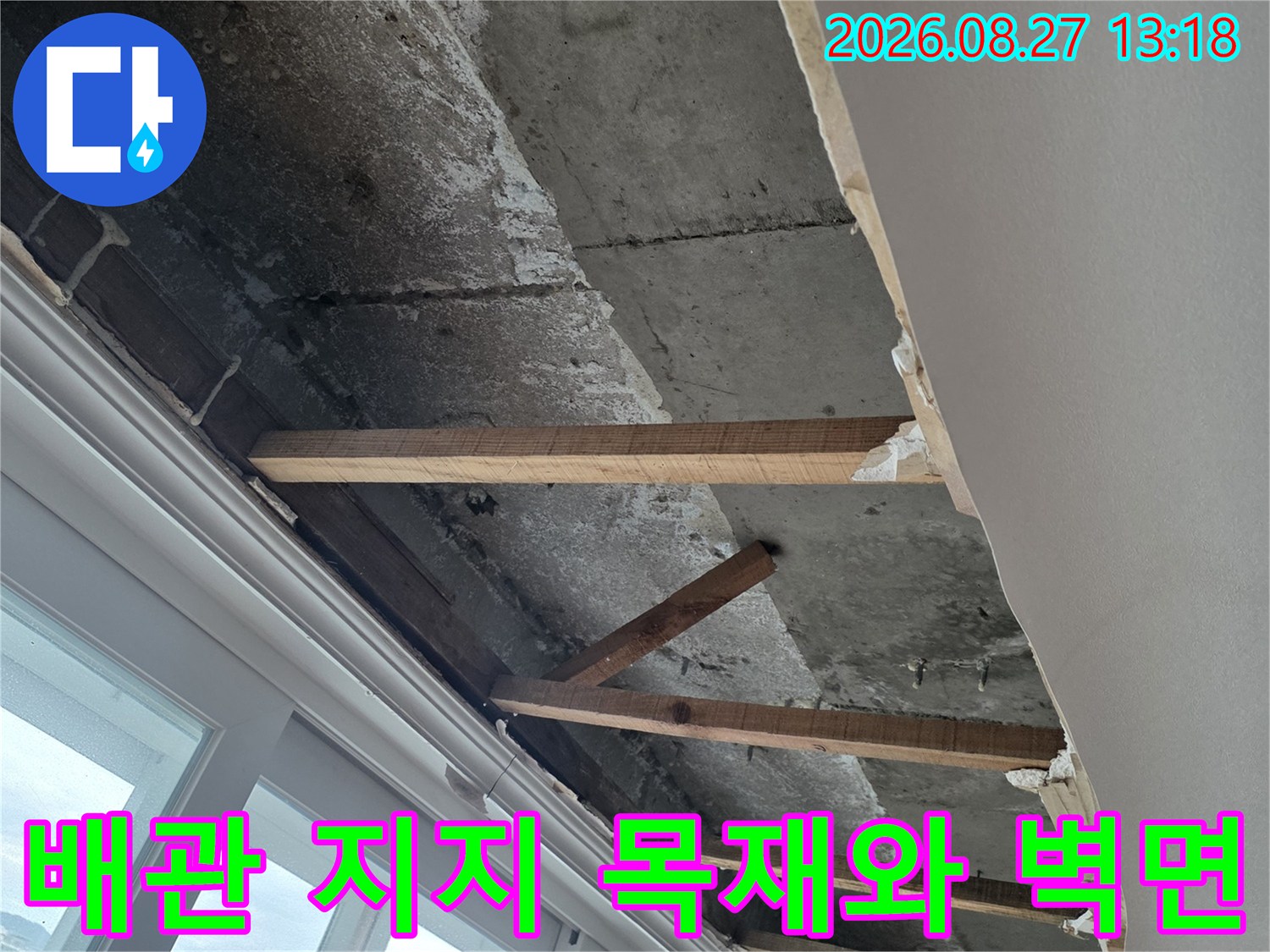 우수관 배관 주변의 노출된 목재 틀과 콘크리트 벽면 상태입니다.