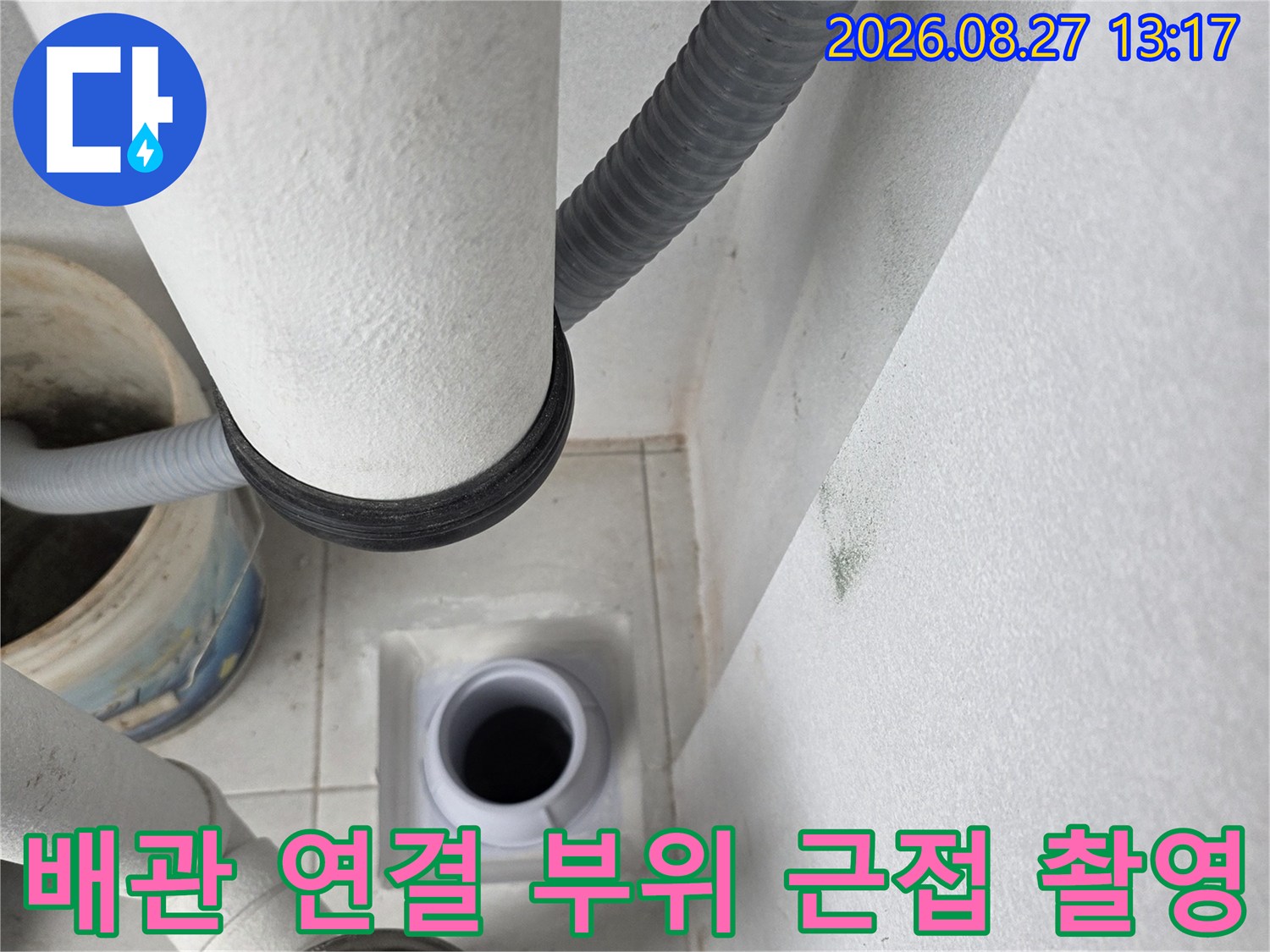 우수관 주변의 흰색 벽면과 연결된 회색 배관의 상세 모습입니다.