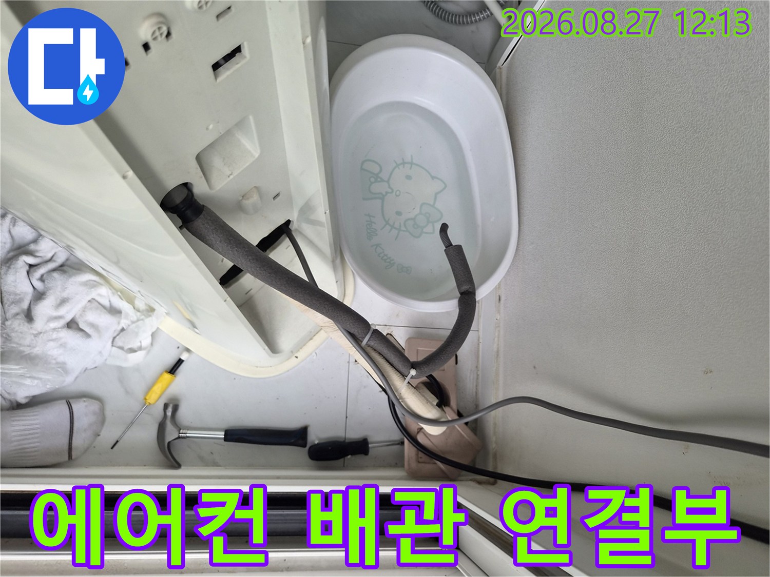 에어컨 하단 드레인 호스와 배수 용기가 놓여 있는 현장 모습입니다.