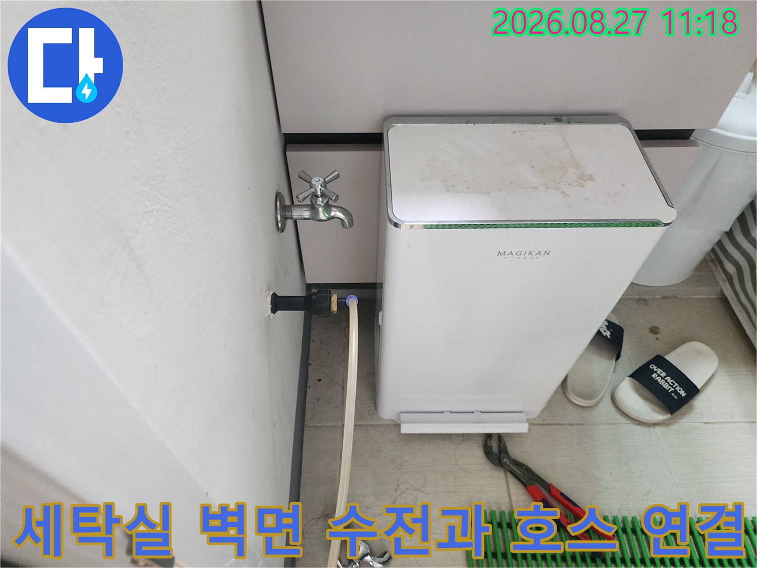 벽면에 설치된 금속제 수전과 흰색 급수 호스의 연결 모습