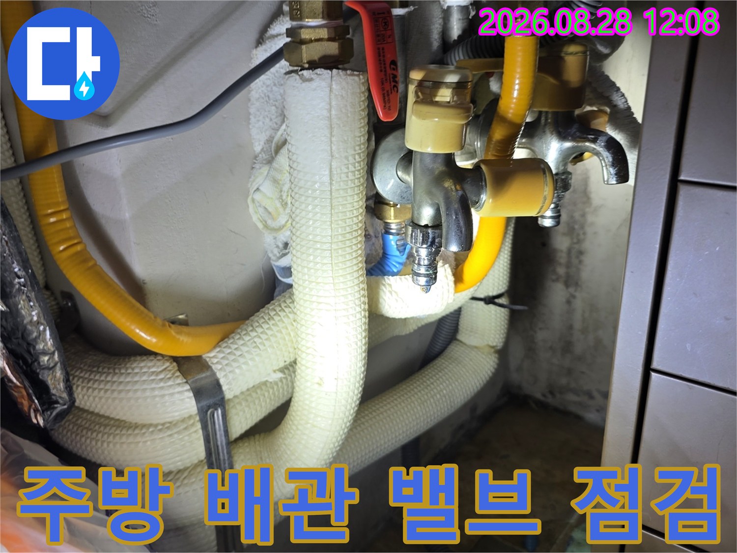 싱크대 하부 금속 밸브와 노란색 보온재가 있는 배관 모습