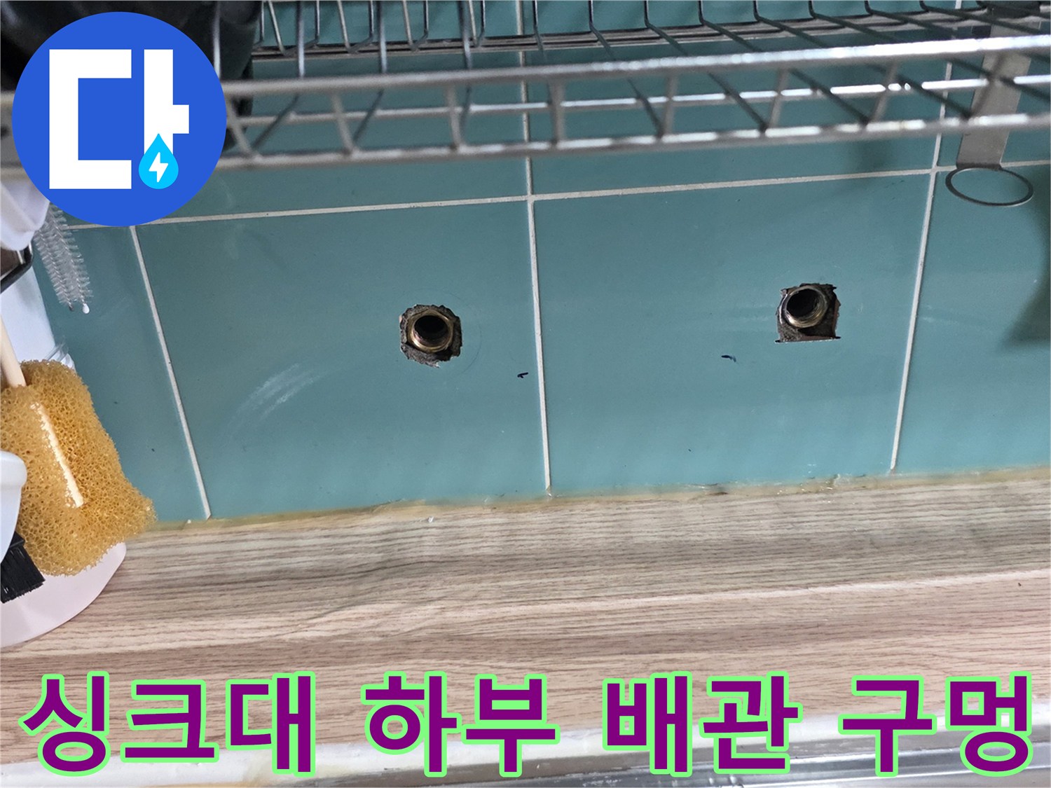 주방 싱크대 아래 타일 벽면에 노출된 배관 연결부