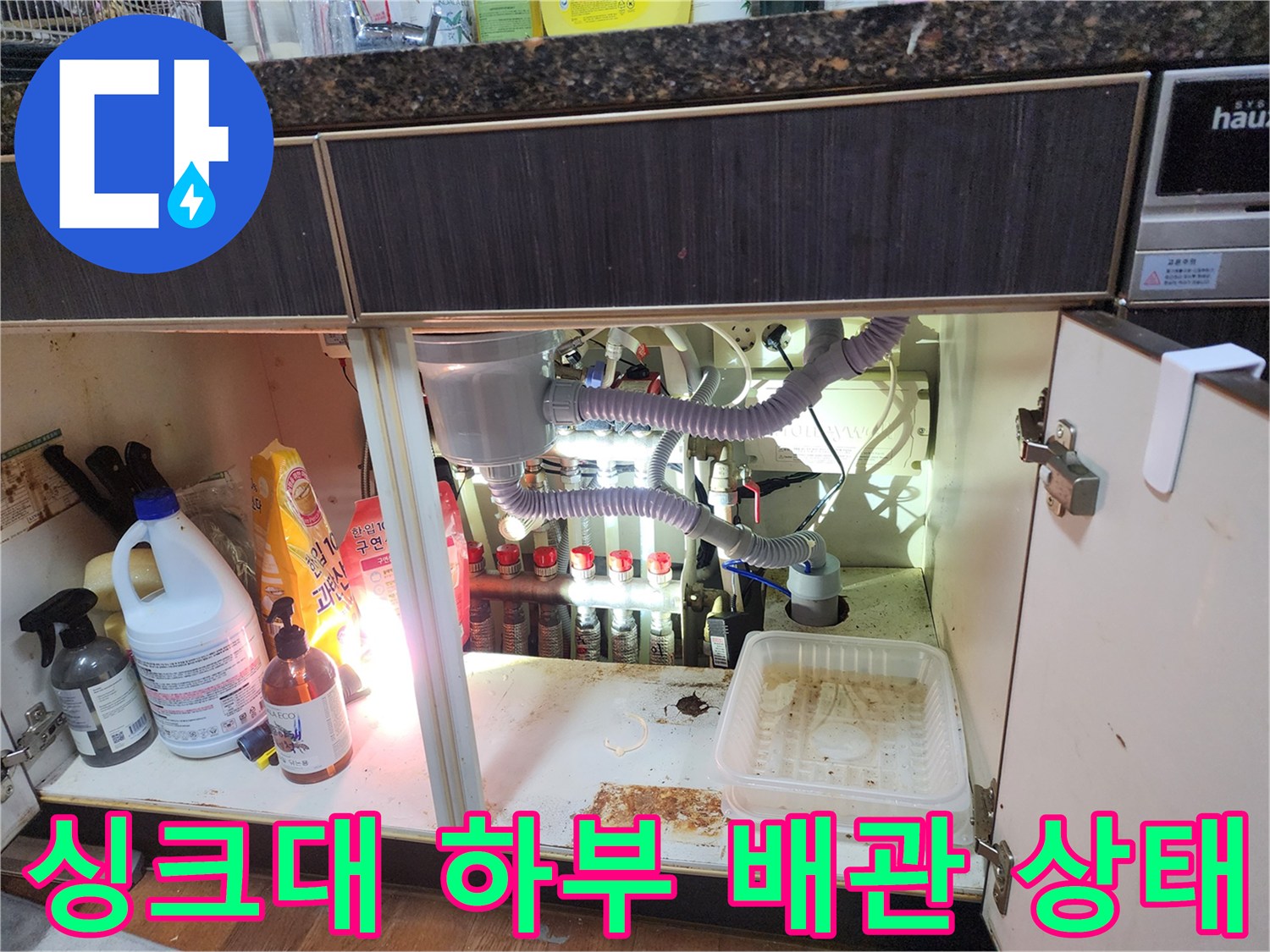 남양주 진접읍 싱크대 아래 에어컨 배수 호스와 각종 세제들이 놓여 있는 모습