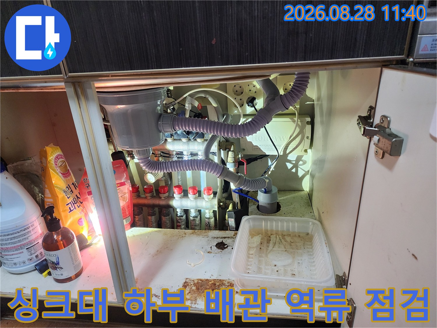 복잡한 정수기 필터와 에어컨 드레인 호스가 얽힌 싱크대 내부