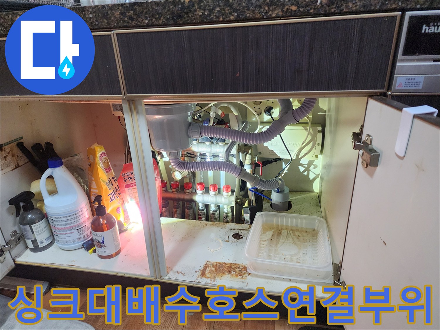 싱크대 아래 복잡하게 연결된 에어컨 및 주방 배수 호스 구조