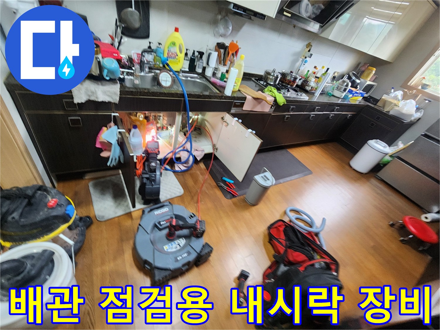 싱크대 아래쪽 작업 공간에 놓인 배관 세척 및 검사용 전문 장비들