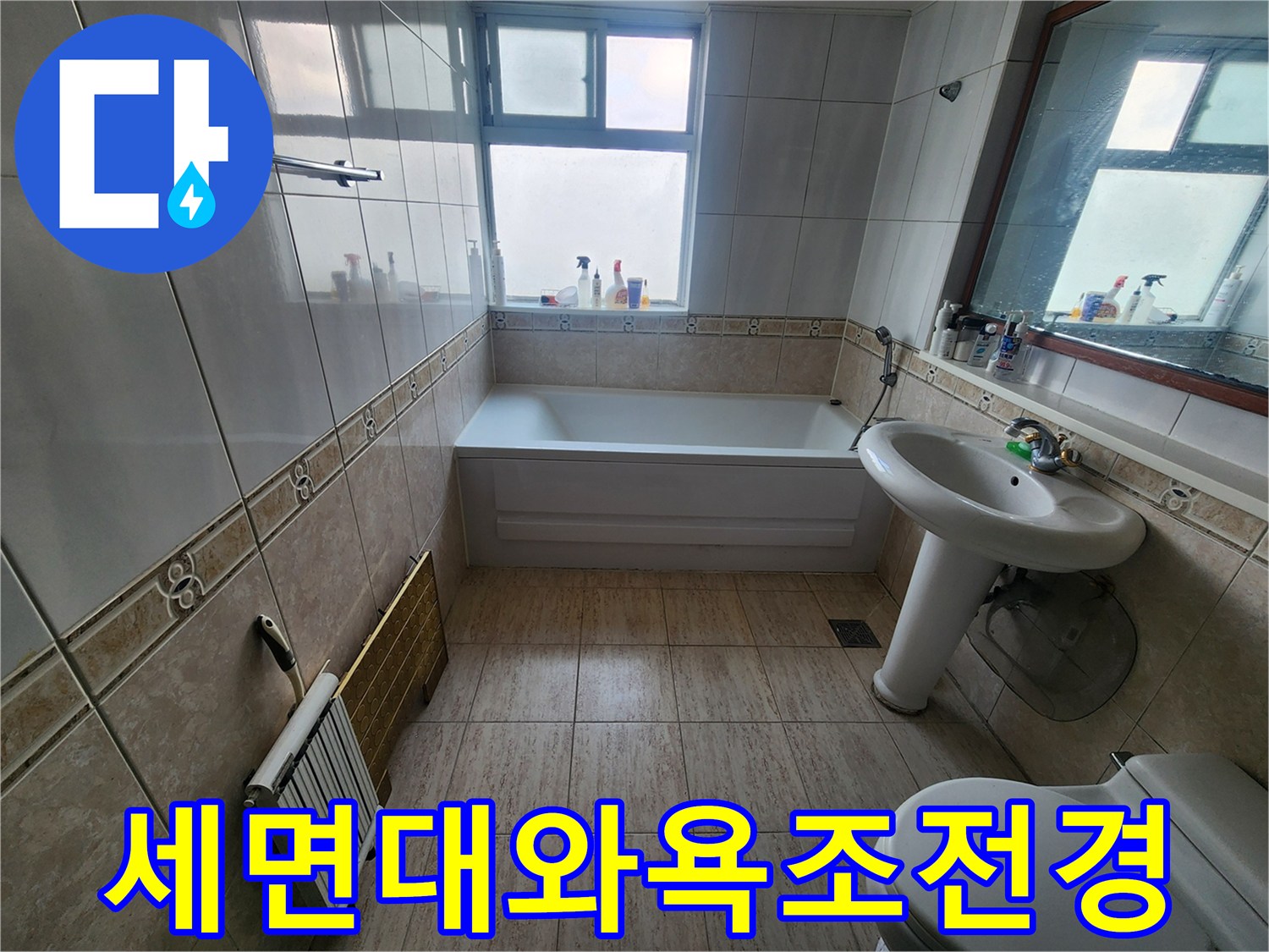 깨끗한 타일로 마감된 욕실의 세면대와 욕조 및 창문 모습입니다.