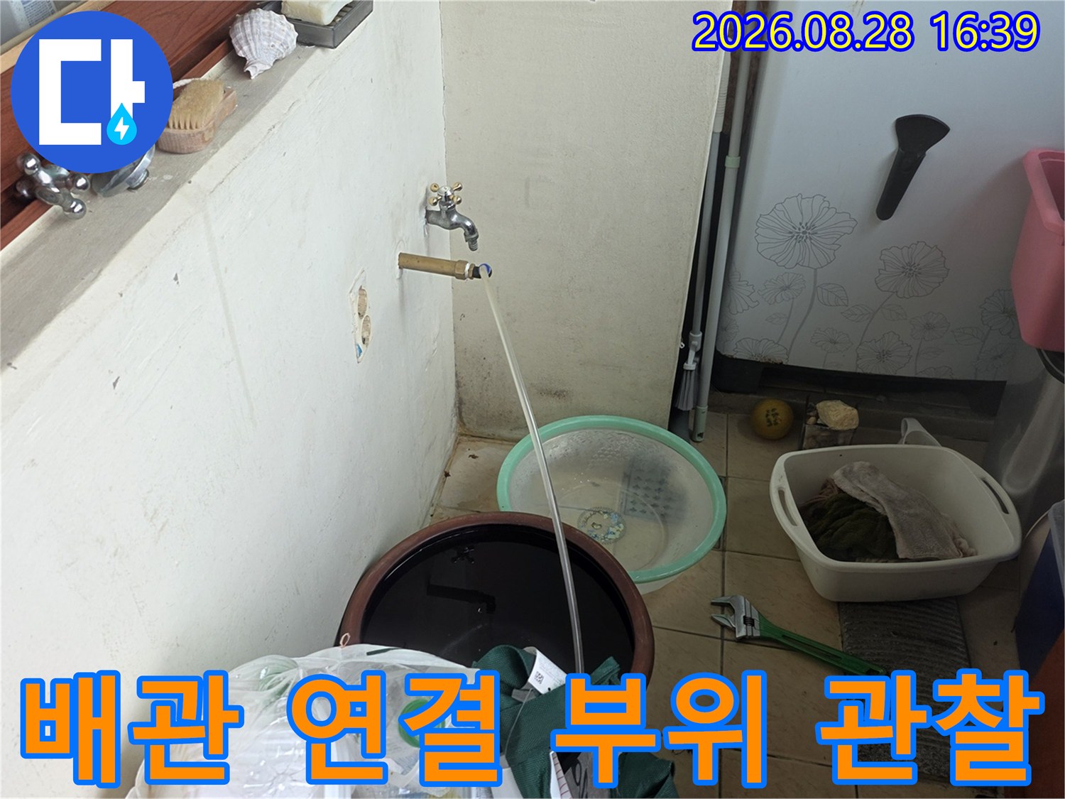 벽면 배관에서 뻗어 나온 호스와 수도꼭지 주변을 점검 중입니다.