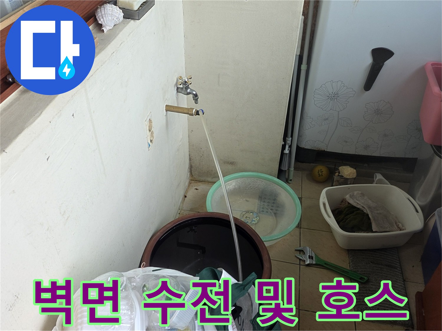 벽면에 고정된 수도꼭지와 연결된 튜브를 촬영한 사진입니다.