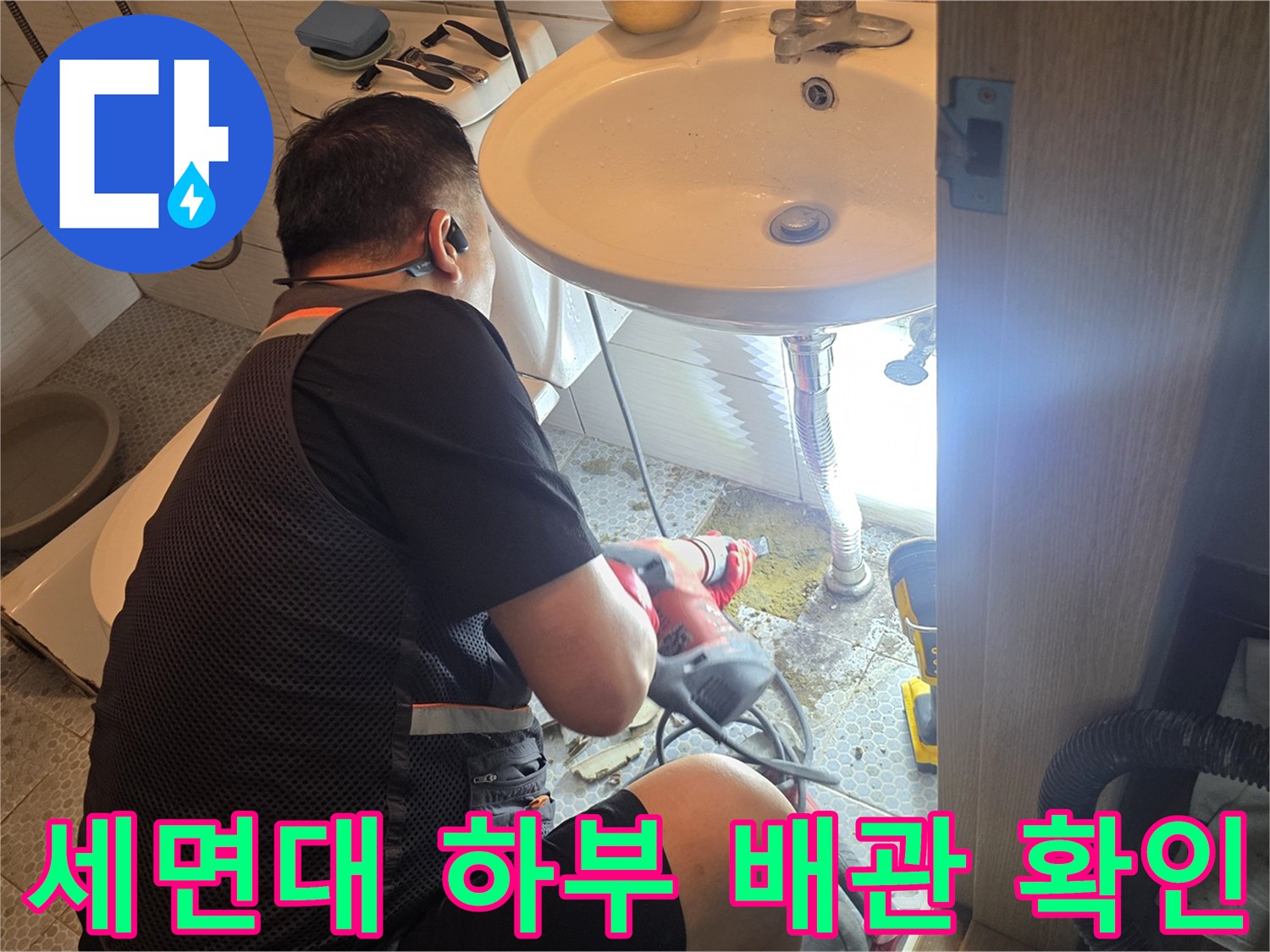 세면대 아래쪽 배관 연결 부위를 면밀히 관찰하는 모습
