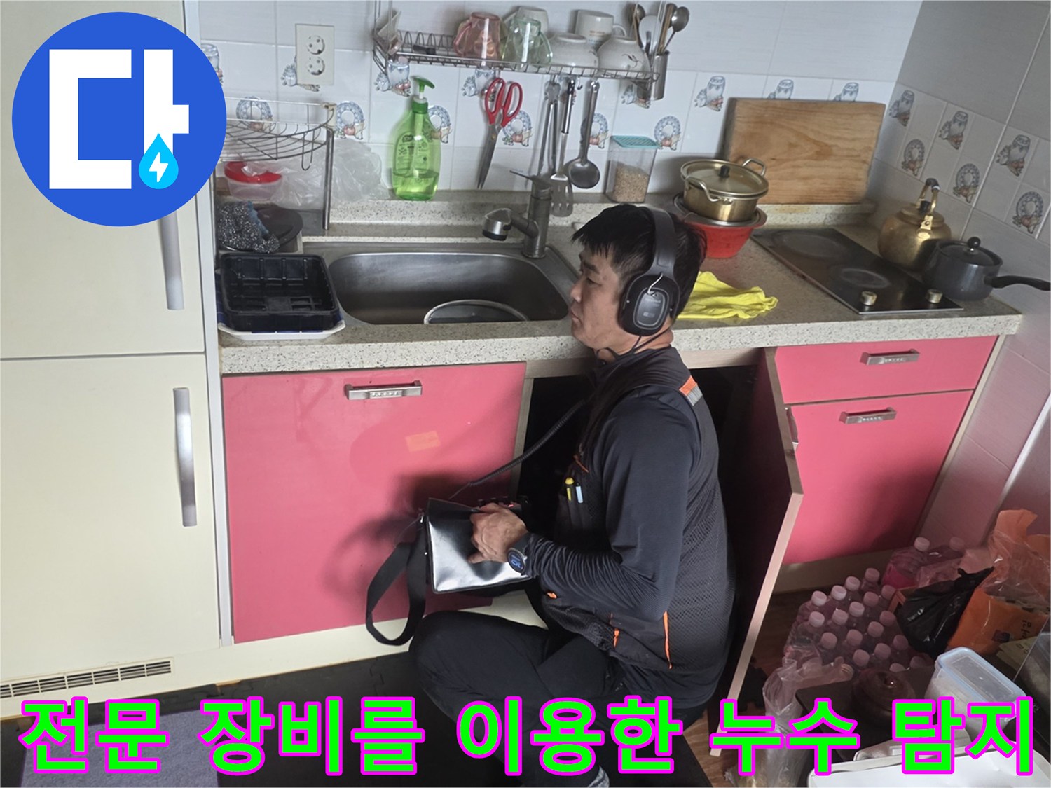 청음식 탐지기를 착용하고 싱크대 밑 배관을 진단하는 모습