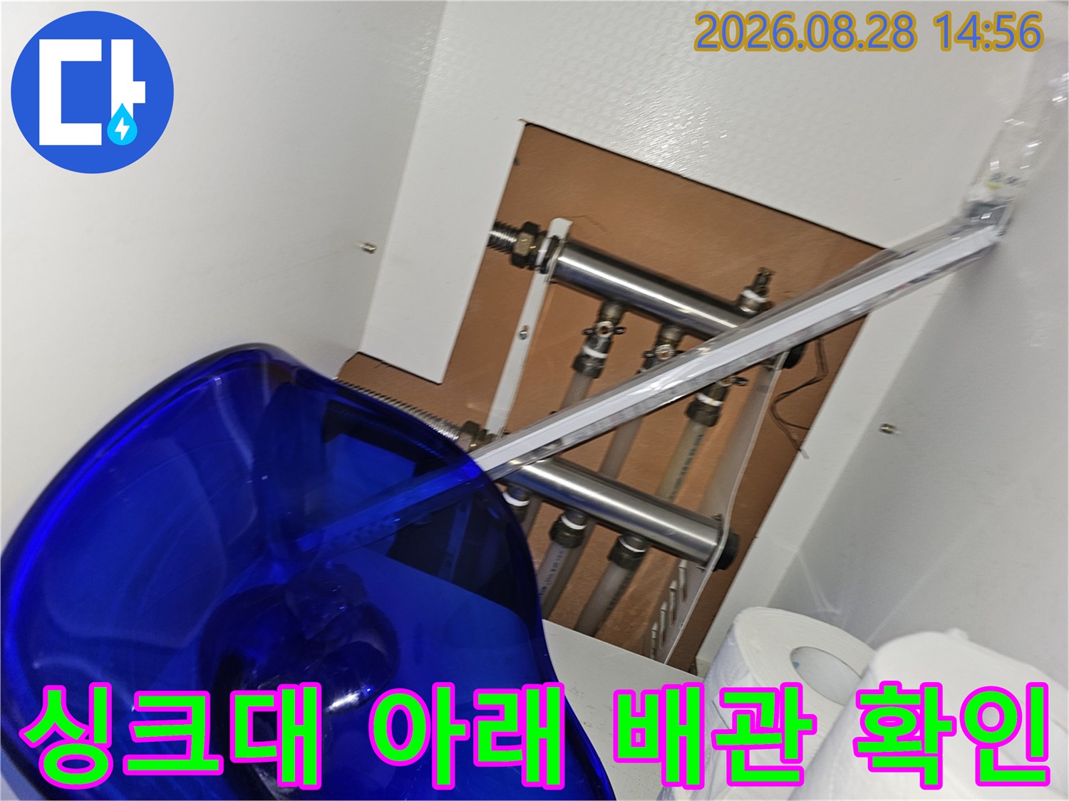 싱크대 하단 공간의 금속 배관들과 연결 부위들의 상세한 모습입니다.