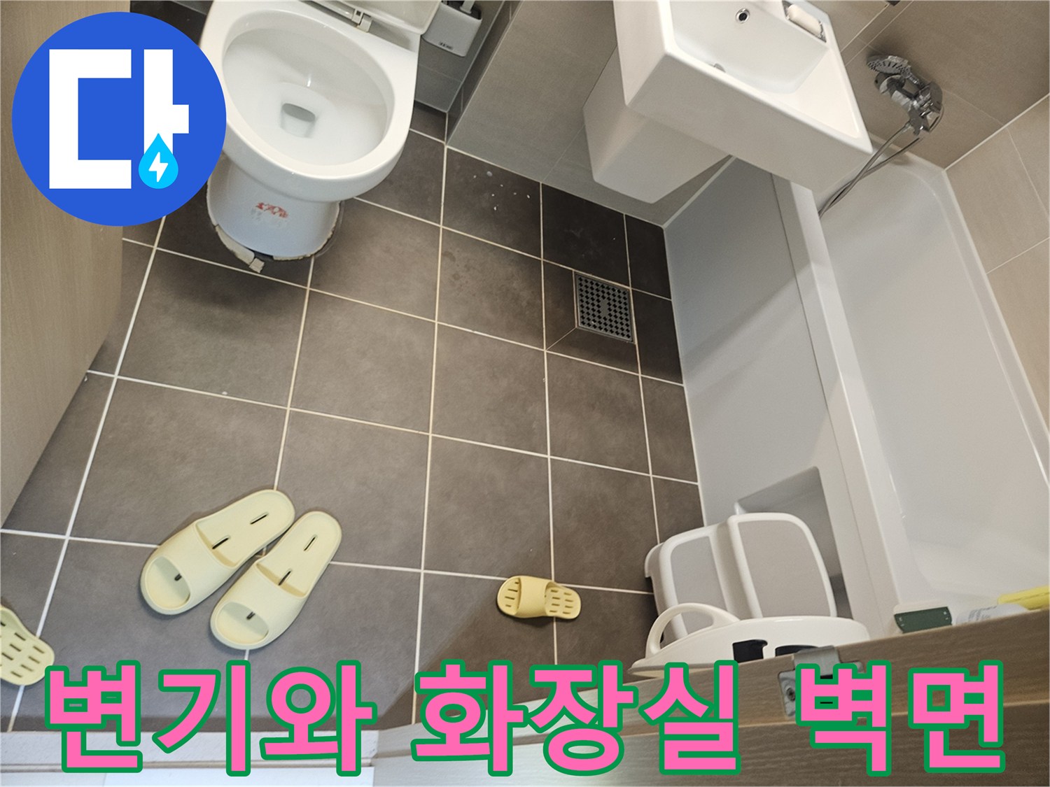 욕실 변기와 회색 타일 벽면 모습