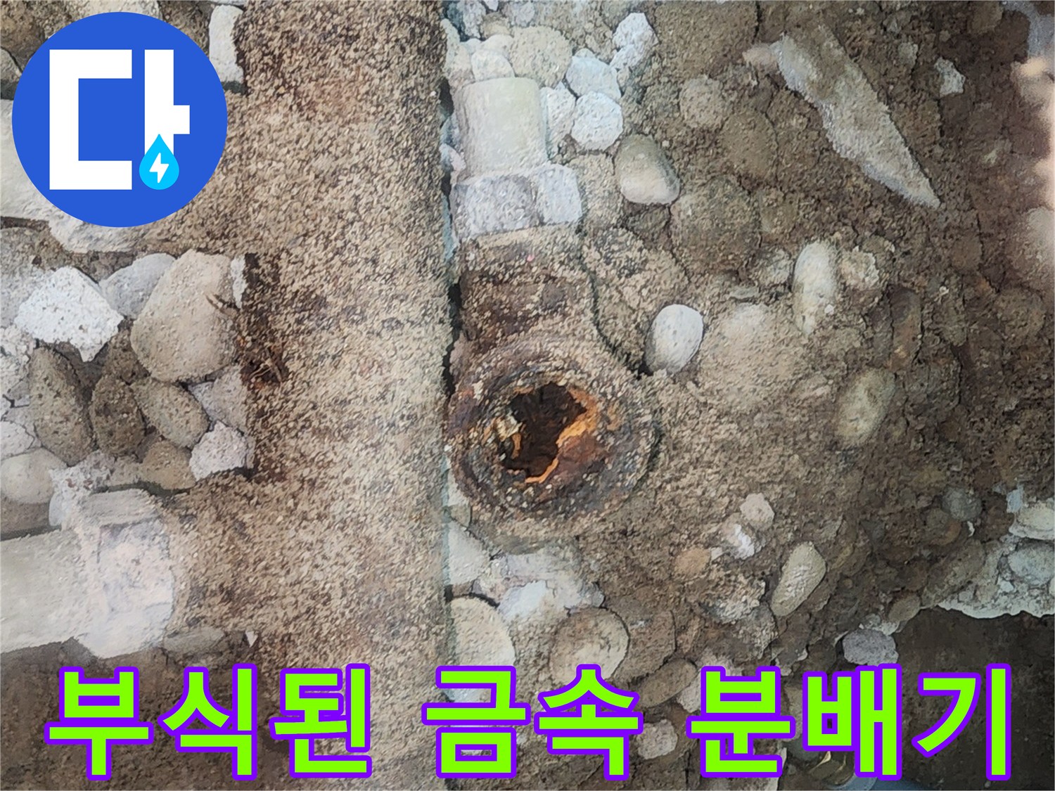 자갈과 토사 사이로 보이는 부식된 배관 연결부