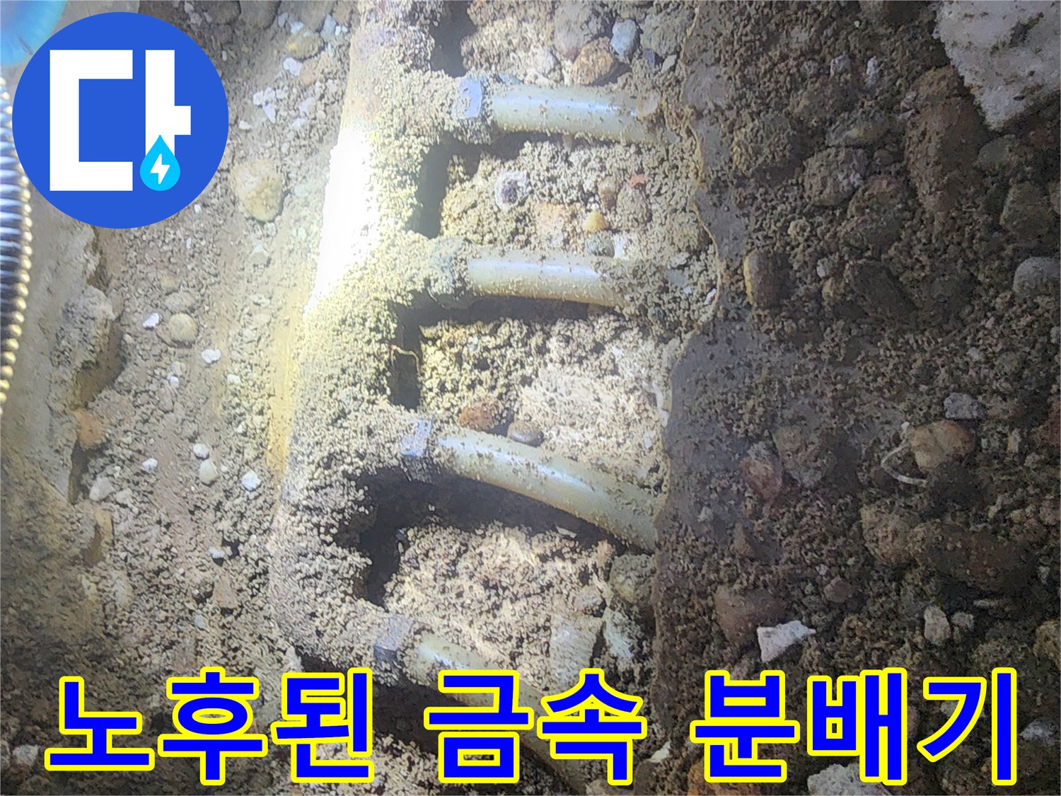 자갈층 아래에 매립되어 부식 진행 중인 금속제 배관 구조물