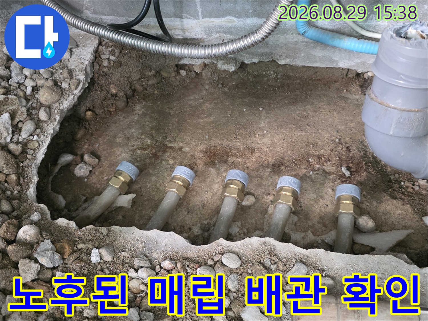 흙과 자갈 속에 노출된 싱크대 하단 분배기 연결 배관의 모습입니다.