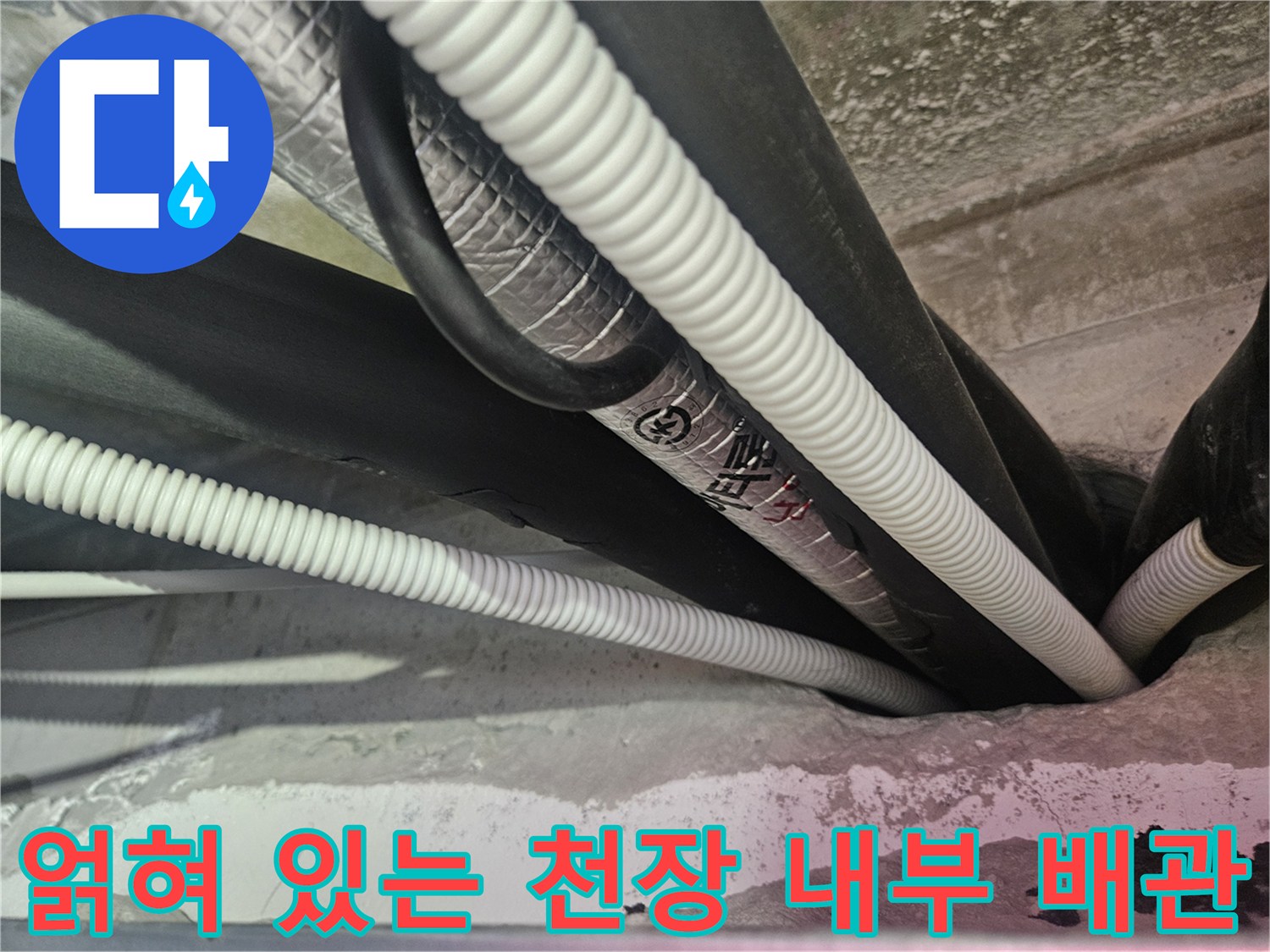 보온재로 감싸진 검은색 배관과 흰색 드레인 호스가 겹쳐진 모습