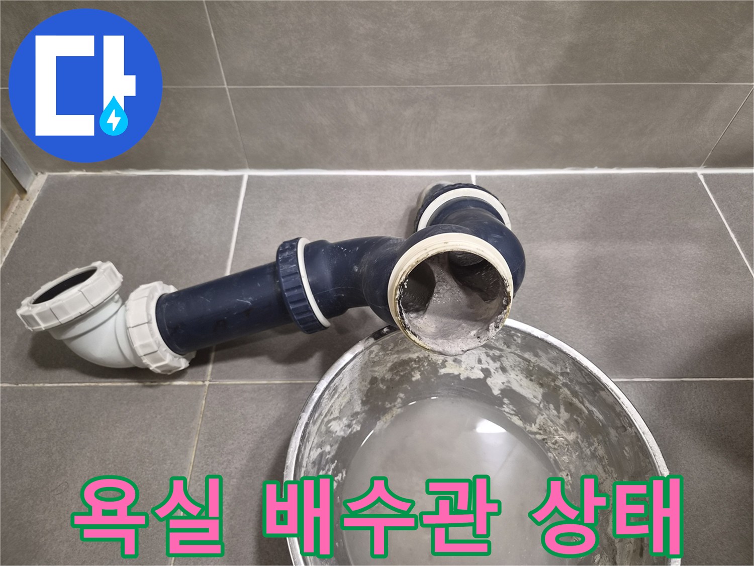 욕실 천장 내부의 파손된 배수 부속과 물이 고인 양동이 모습