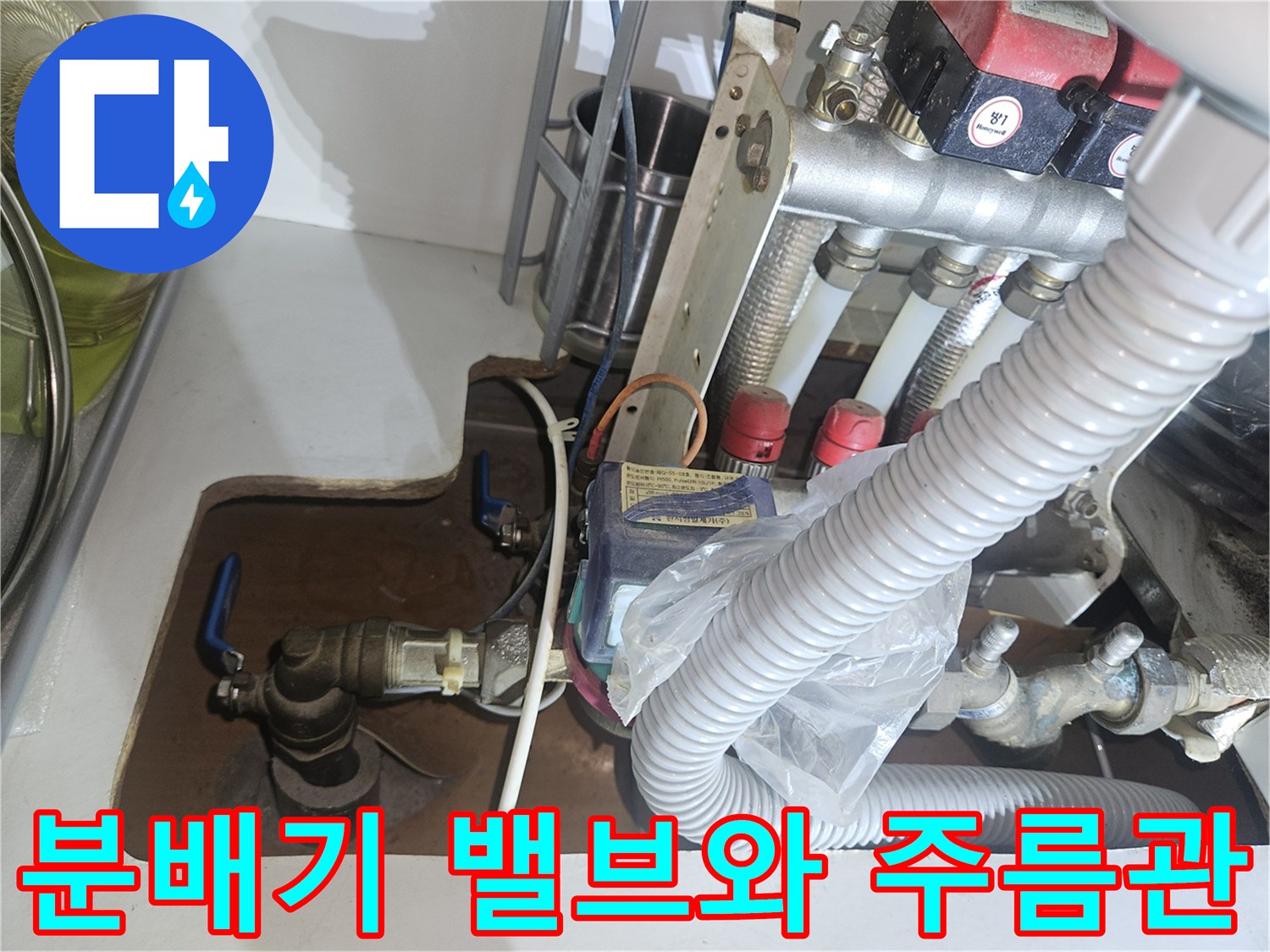 보일러 분배기에 연결된 금속 밸브와 흰색 주름관 상세