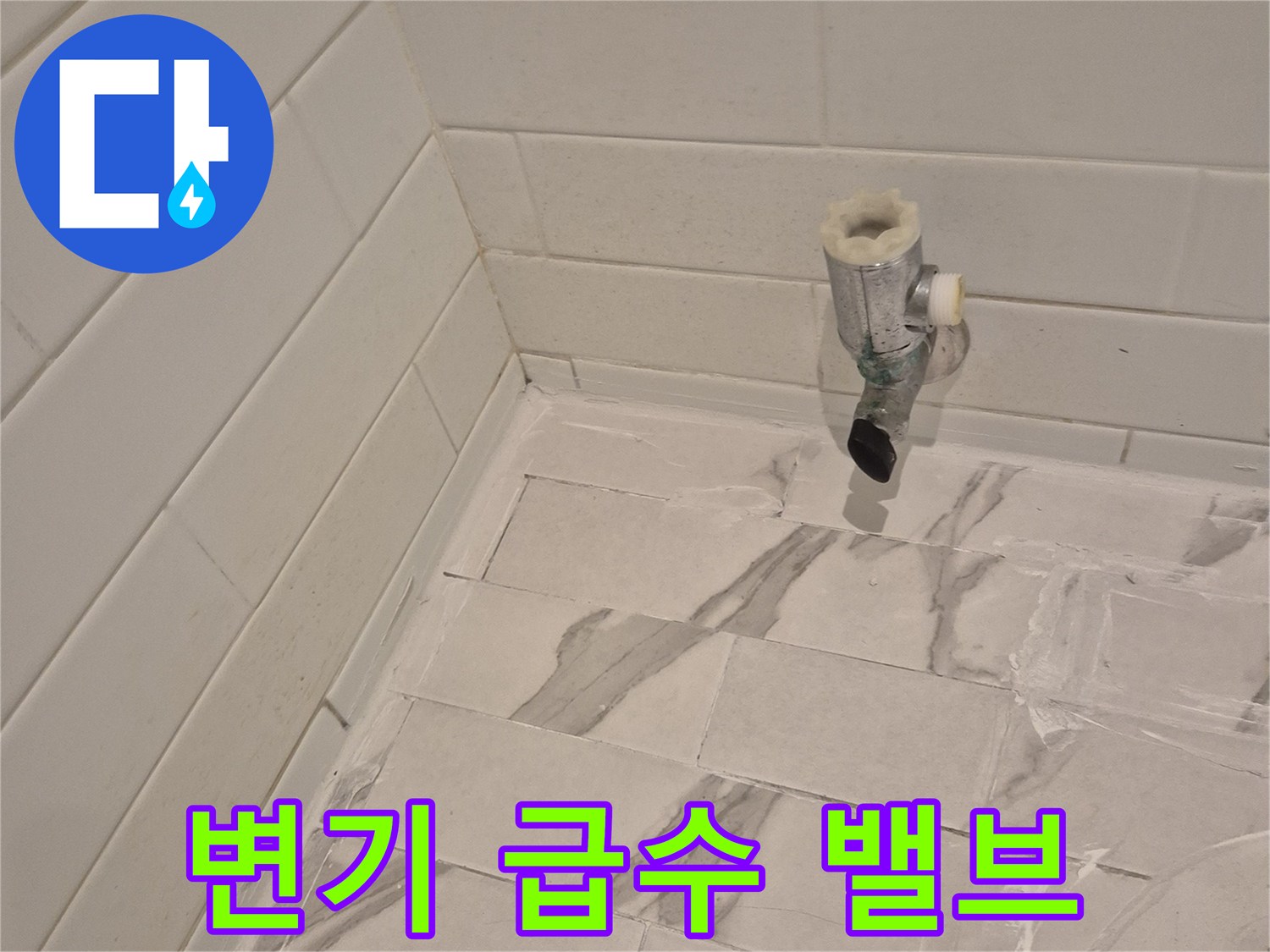 벽면 타일 사이로 돌출된 수도 밸브와 연결 배관 모습