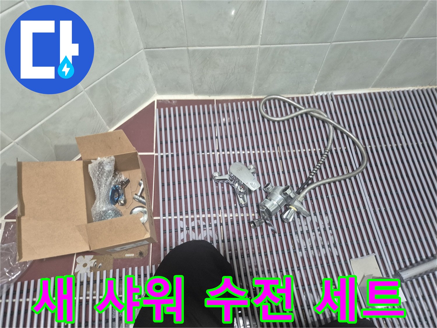 바닥 배수구 근처에 놓인 샤워기 수전과 호스 뭉치
