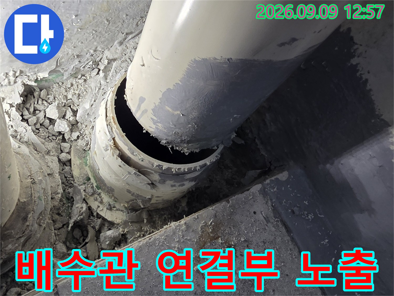 배수관 주변의-흩어진 시멘트 가루와 드러난 관 연결 부위
