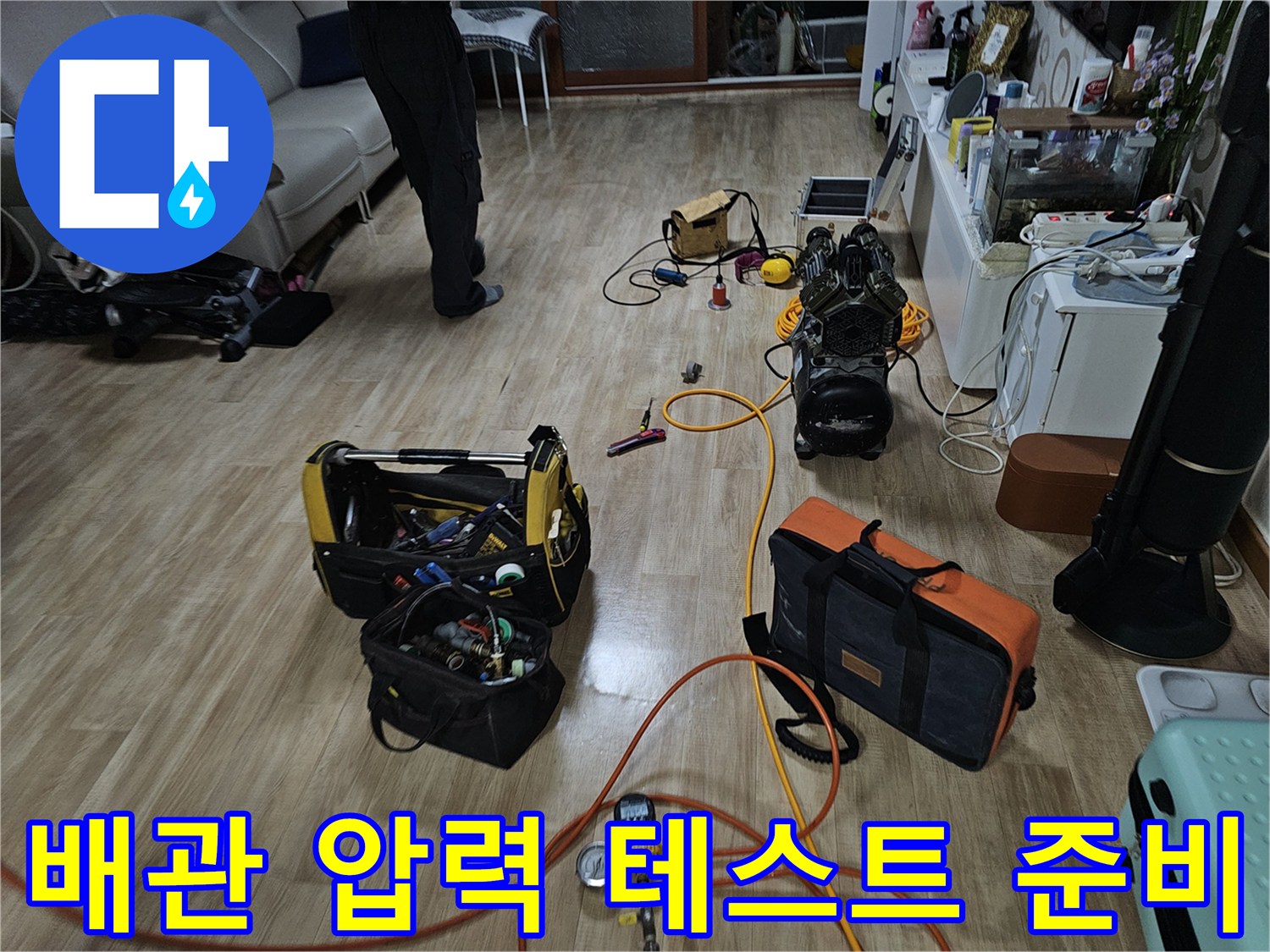거실 바닥에 펼쳐진 누수 탐지용 공압 장비와 가스 연결 호스