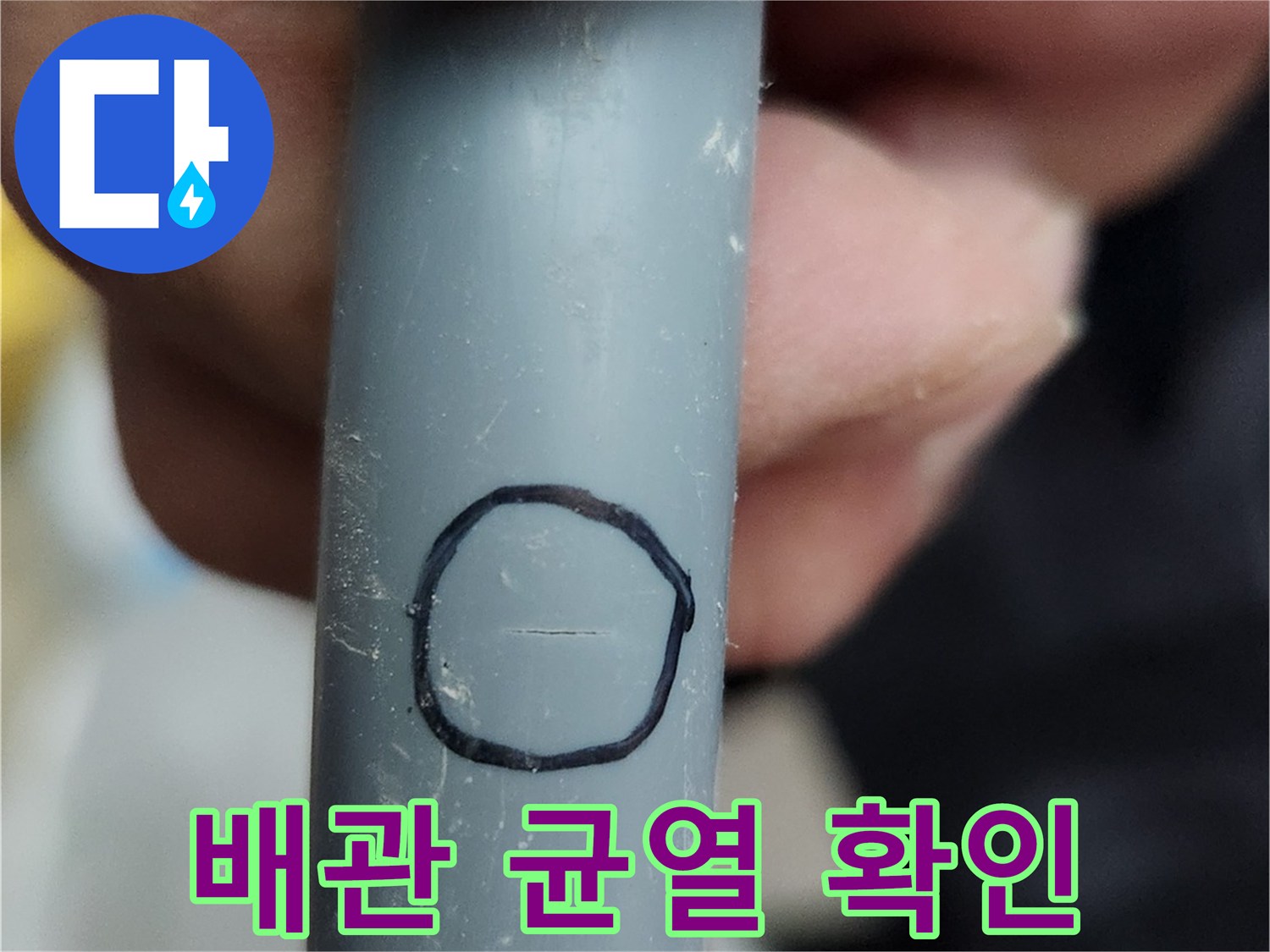 손가락으로 가리키고 있는 배관의 파손된 틈새