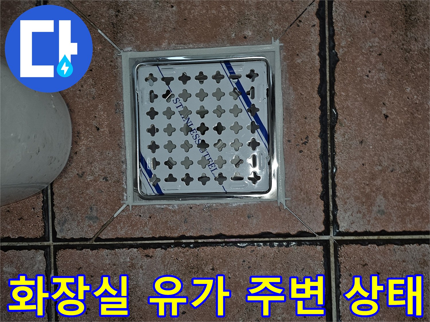 스테인리스 재질의 화장실 배수구 덮개와 주변 타일 모습