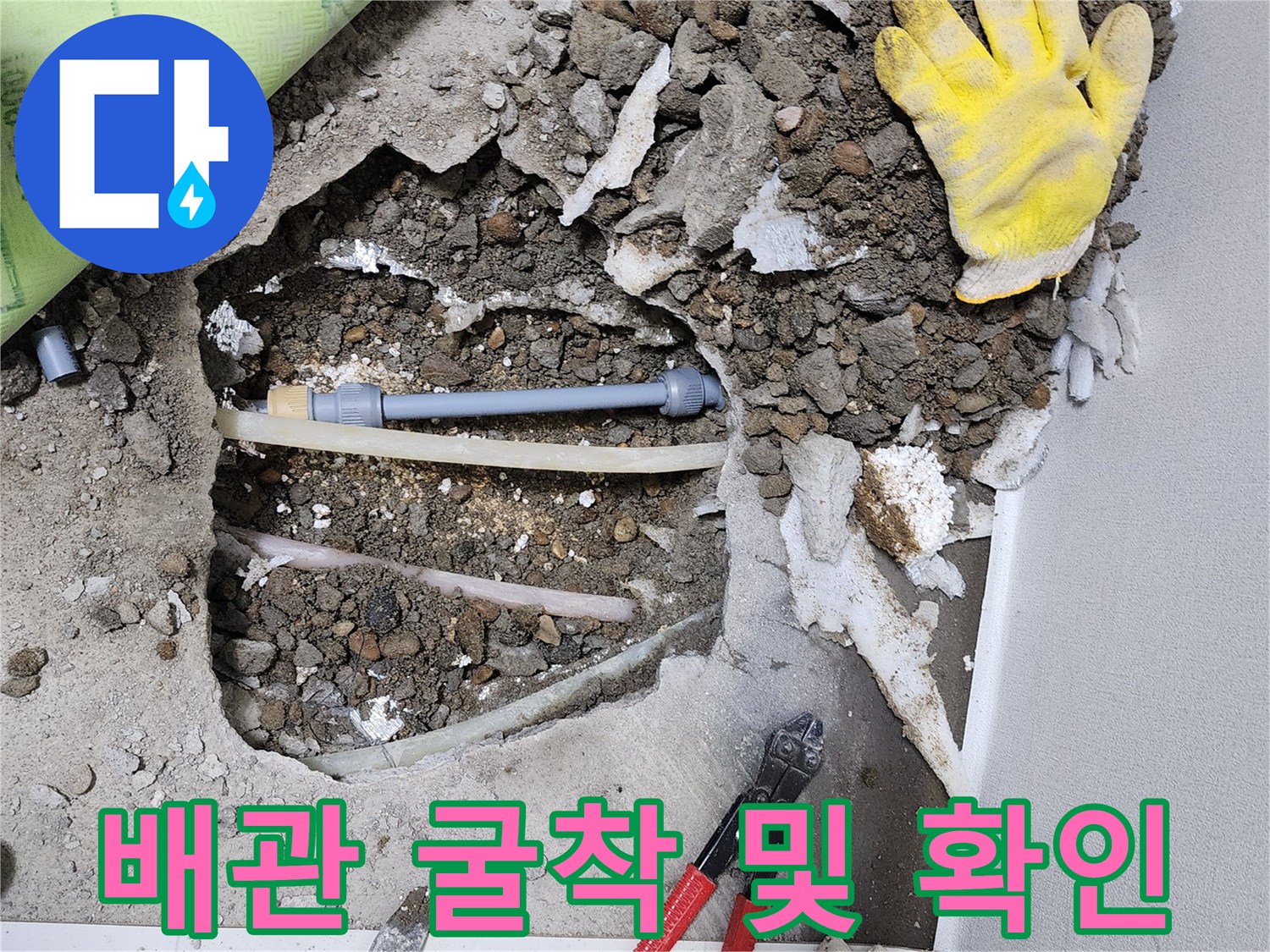 콘크리트 바닥을 깨서 드러낸 수도 배관과 작업 도구