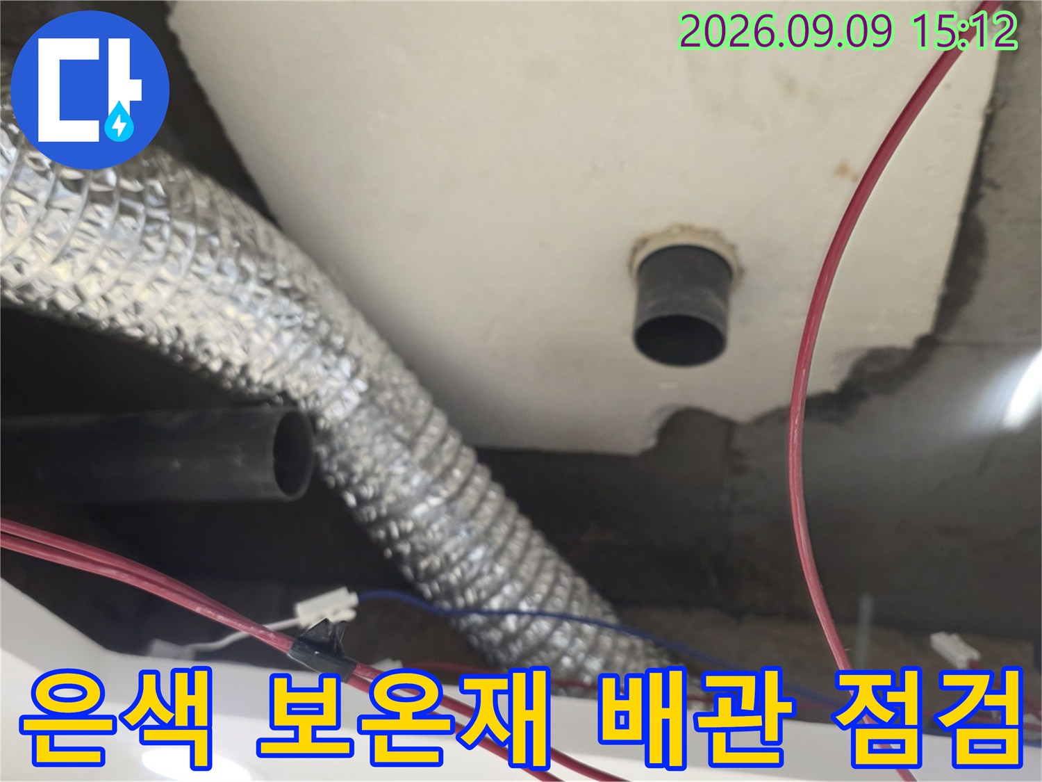 천장 내부의 은박 보온재로 감싸진 하수관과 검은색 배관 연결 부위